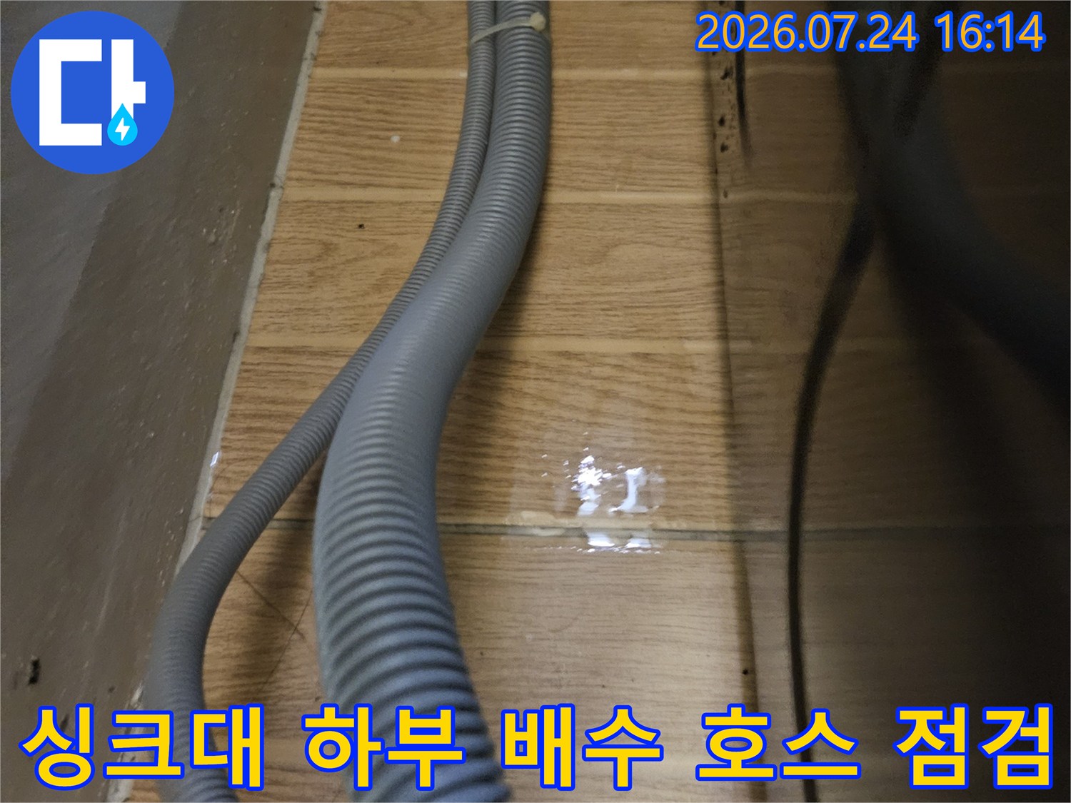 주방 싱크대 아래 설치된 회색 배수 호스와 벽면 연결 부위 점검 사진