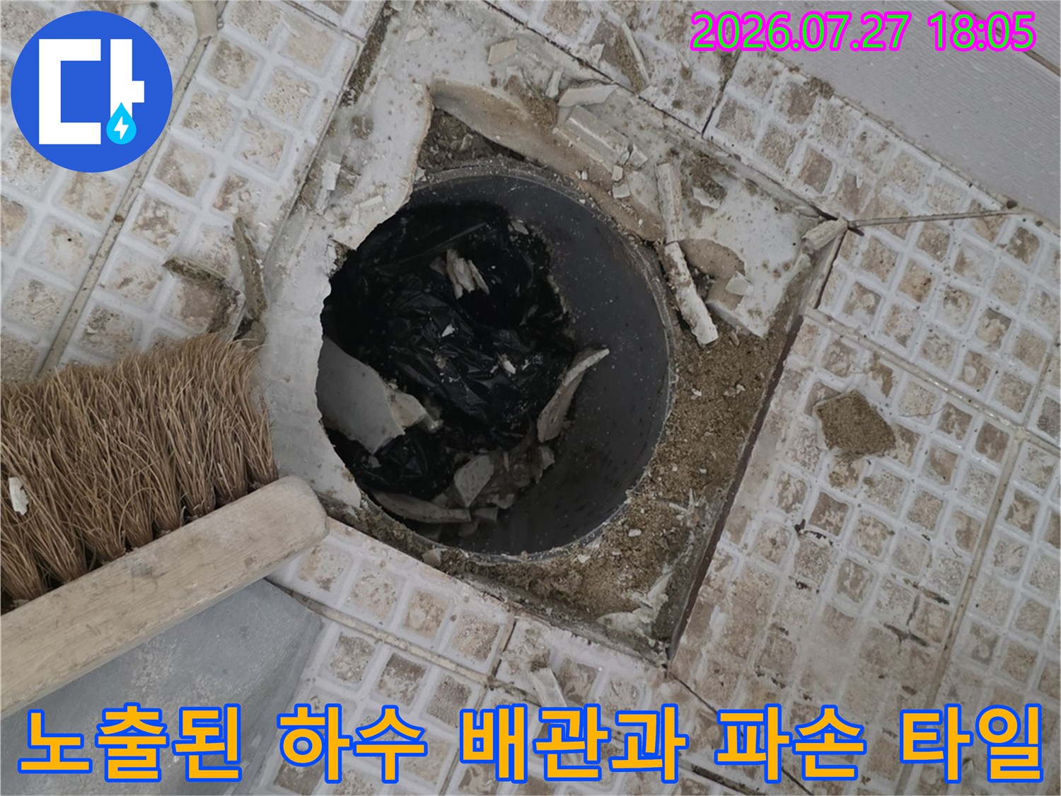 배수구 주변의 깨진 타일 조각들과 내부 검은색 배관 모습-방수 공사 전 단계