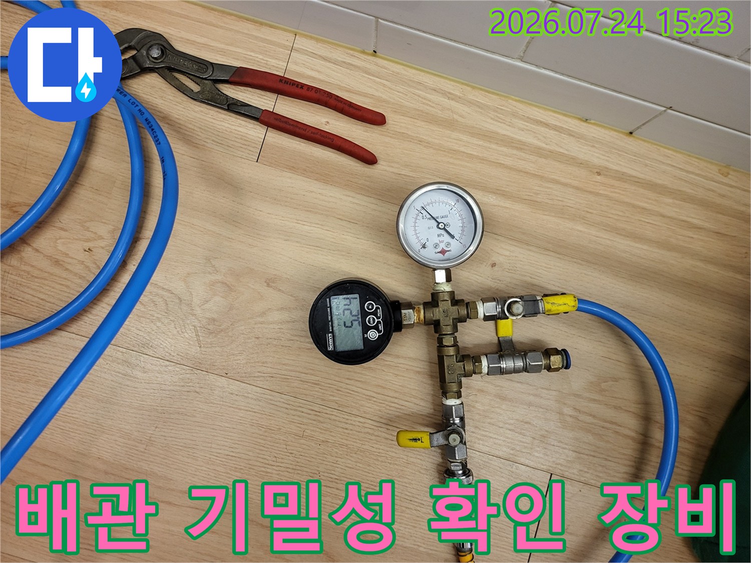 금속 밸브와 압력 게이지들이 연결된 형태의 배관 검사용 측정 장치-파란색 호스 연결