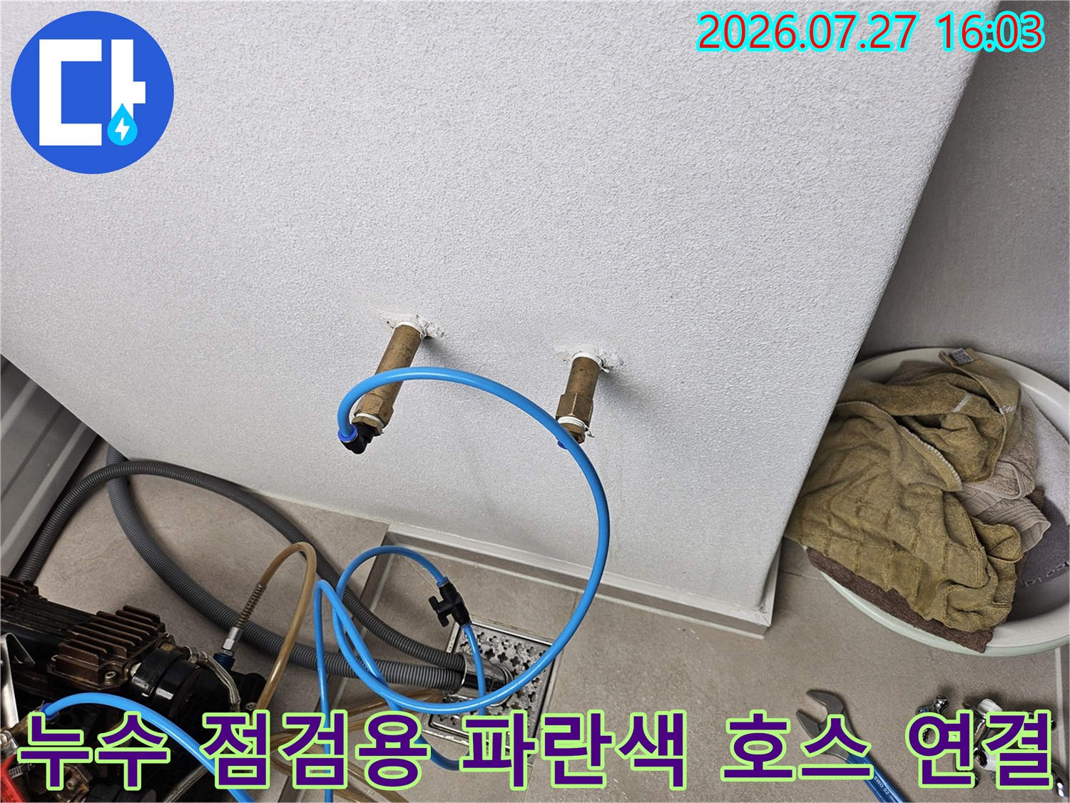 배관 끝단에 파란색 고무 호스를 연결하여 압력을 측정하고 있는 모습