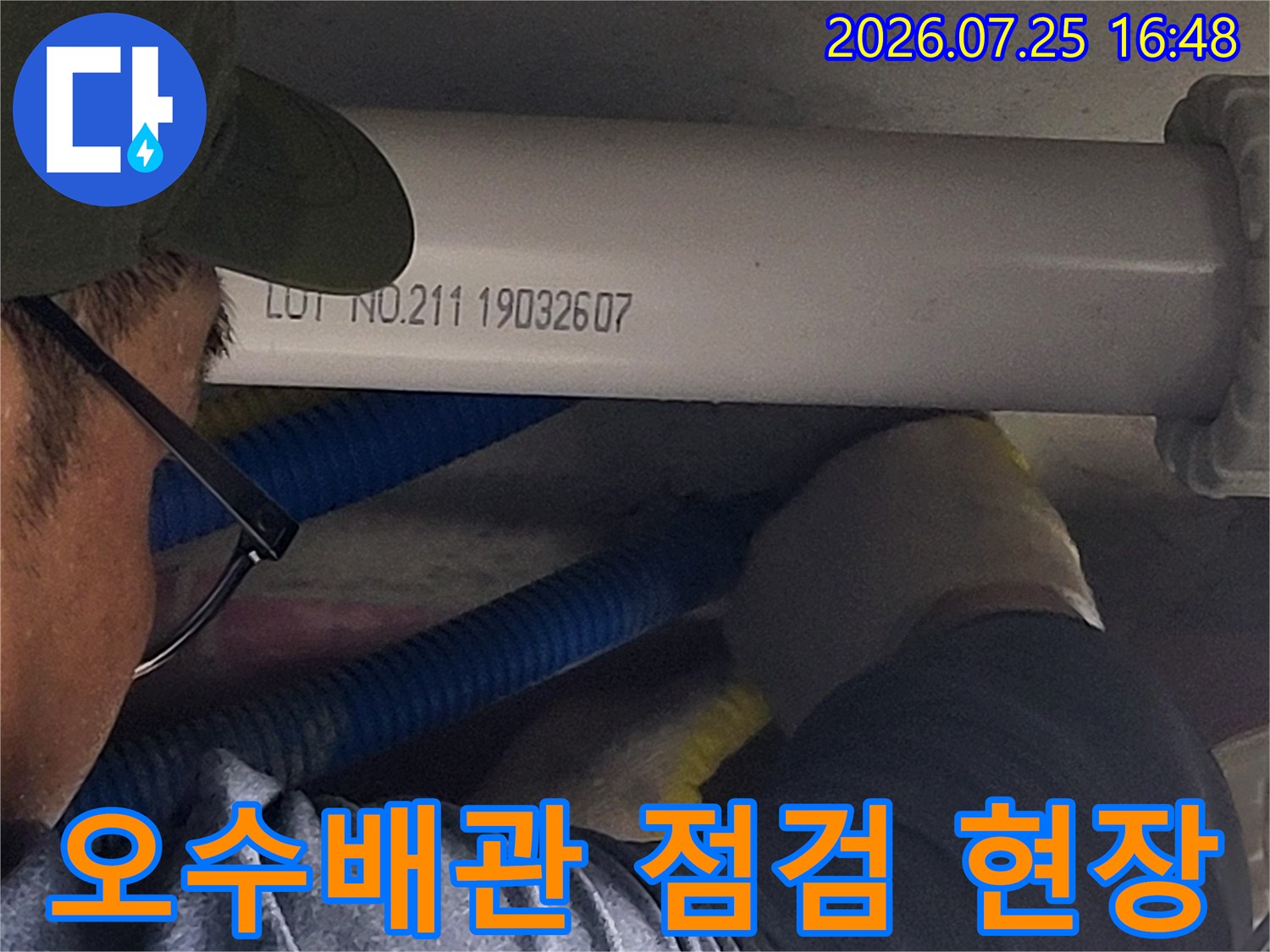 작업자가 장갑을 끼고 수직으로 세워진 흰색 배관을 점검하는 모습