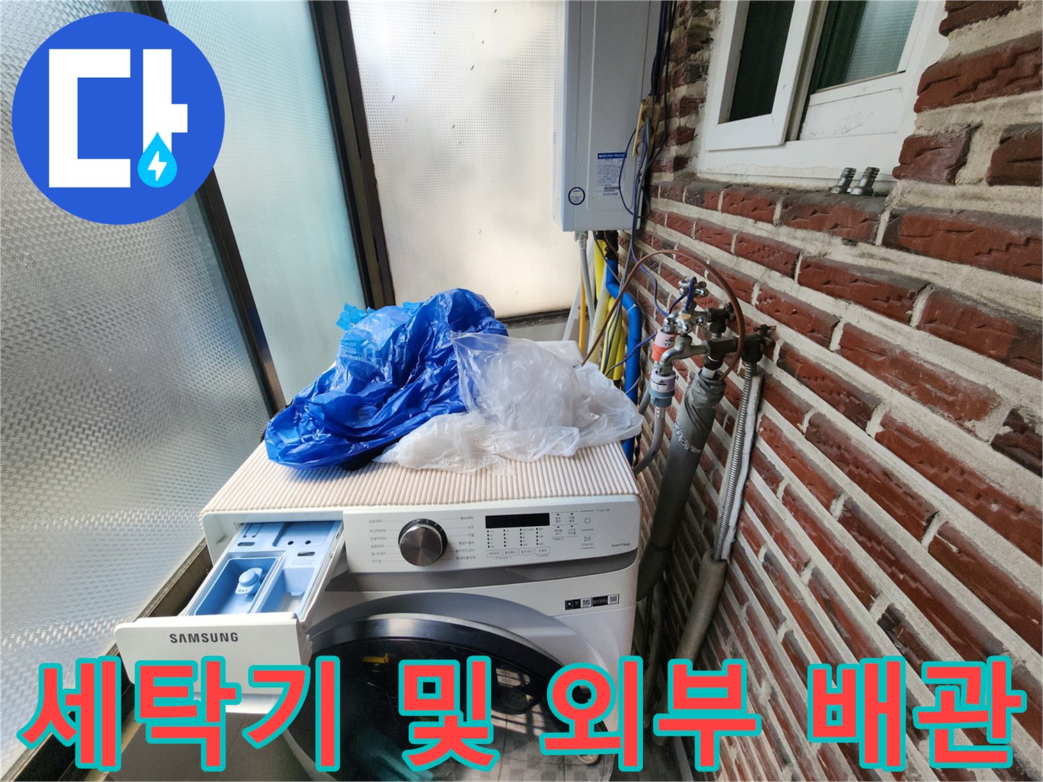 세탁기 뒤쪽 벽돌 외벽에 설치된 수도 계량기와 노출 배관