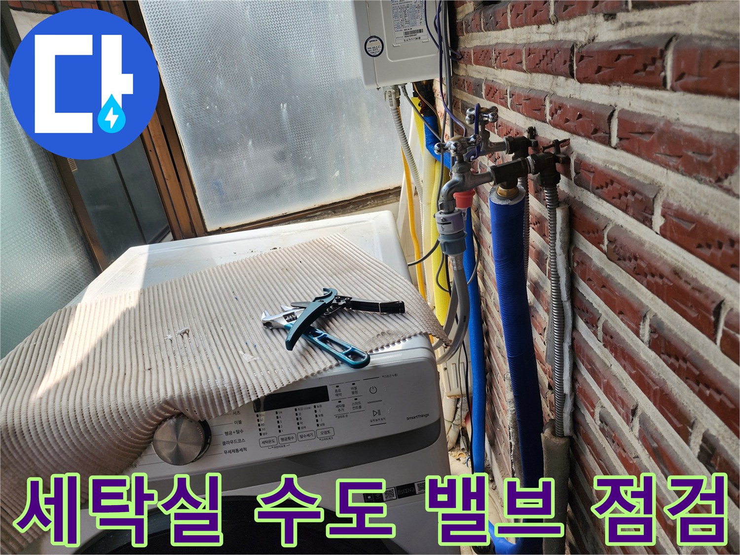 세탁기 옆 벽면의 파란색 보온 배관과 금속 수전 장치