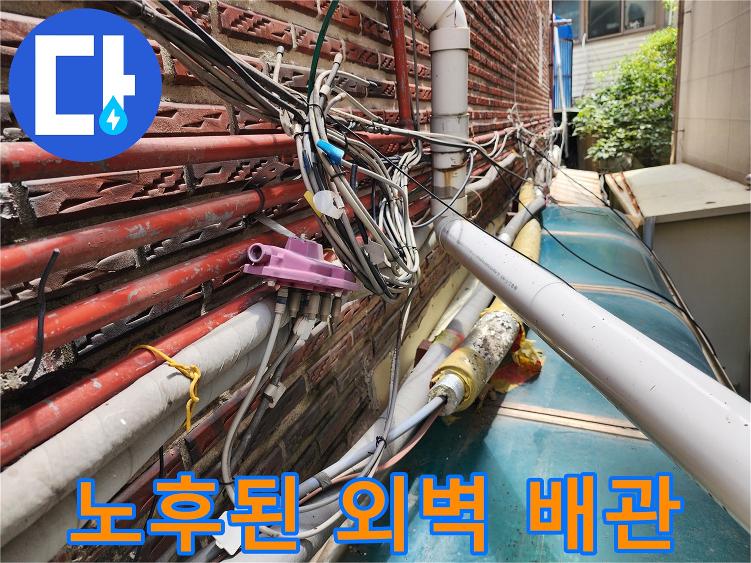 외벽 벽돌에 고정된 노출 배관들과 낡아서 탈락한 보온재의 모습