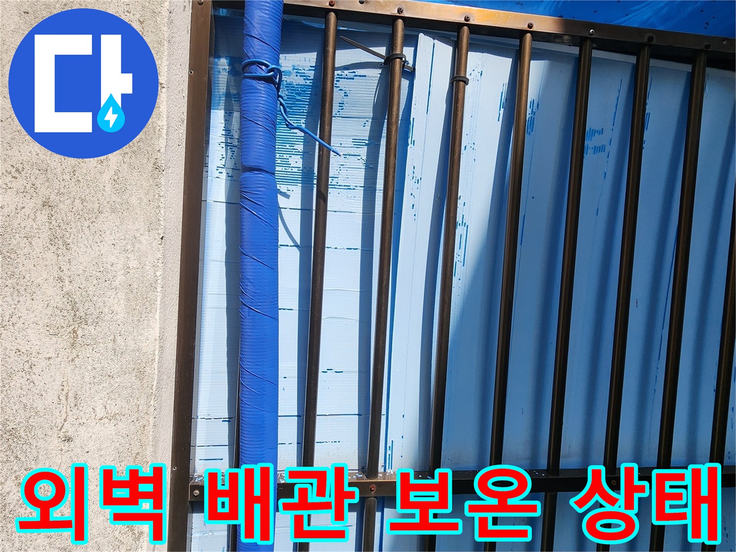 외벽에 설치된 파란색 보온재로 감싸진 배관의 모습입니다.