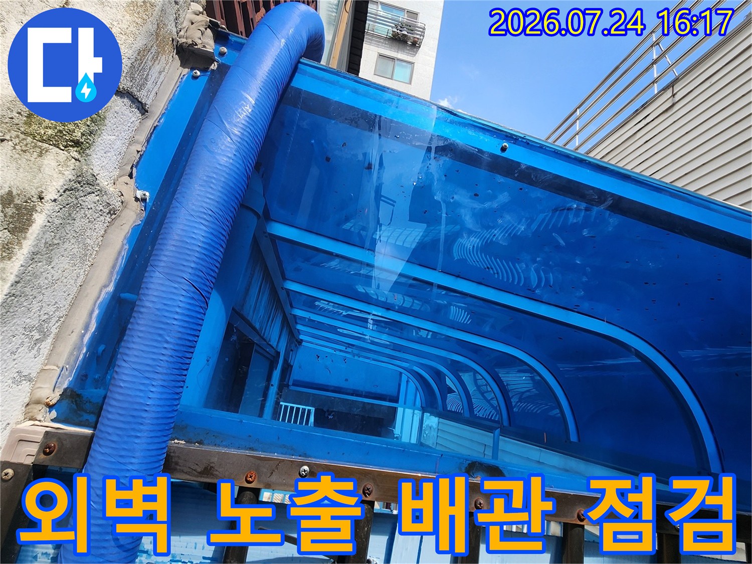 파란색 보온재로 감싸진 외벽 노출 배관과 벽돌 담장 상태