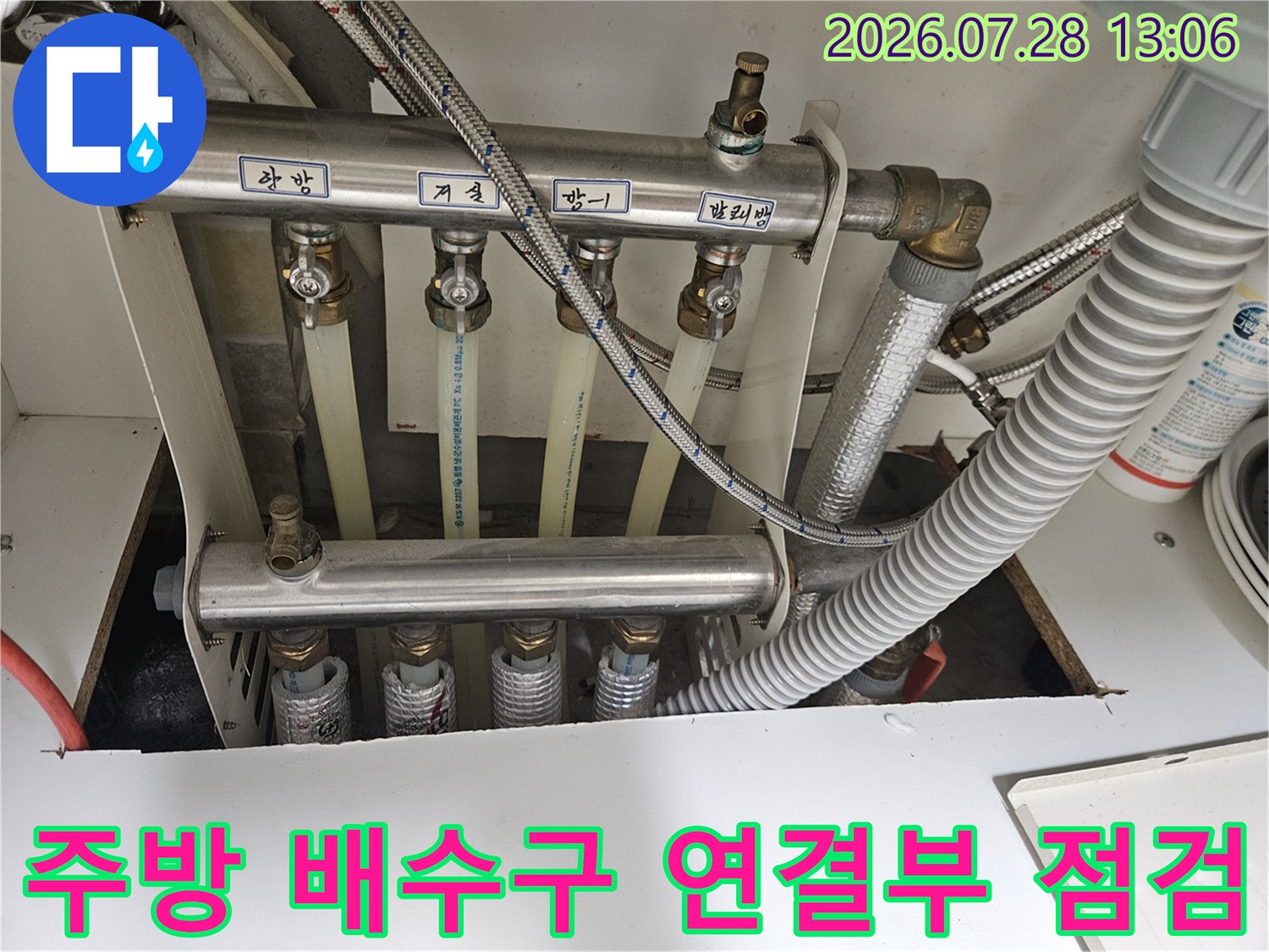 싱크대 내부의 복잡한 배수관 구조와 노출된 파이프라인을 촬영한 이미지