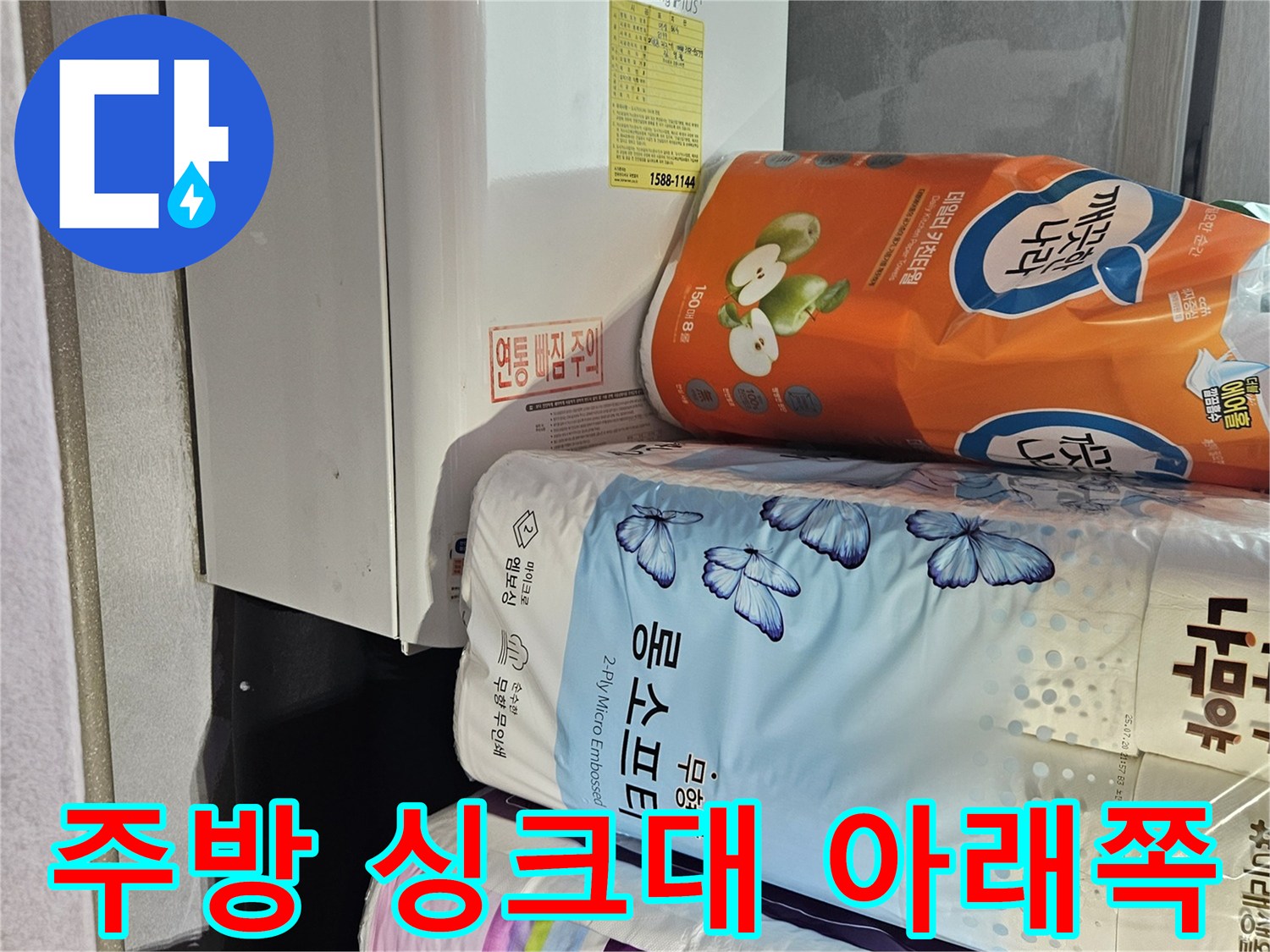 싱크대 밑에 놓인 다양한 생활용품과 가전제품들