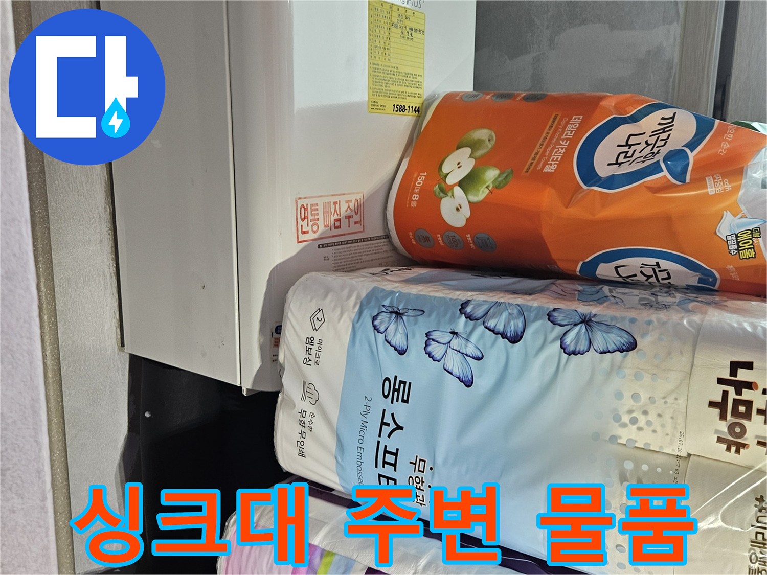 주방 싱크대 하단에 놓인 생활용품과 가전제품 모습