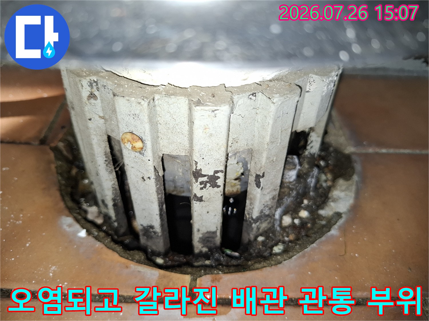 배관 주위의 하얀색 마감재가 깨지고 검은색 물때와 곰팡이가 낀 모습