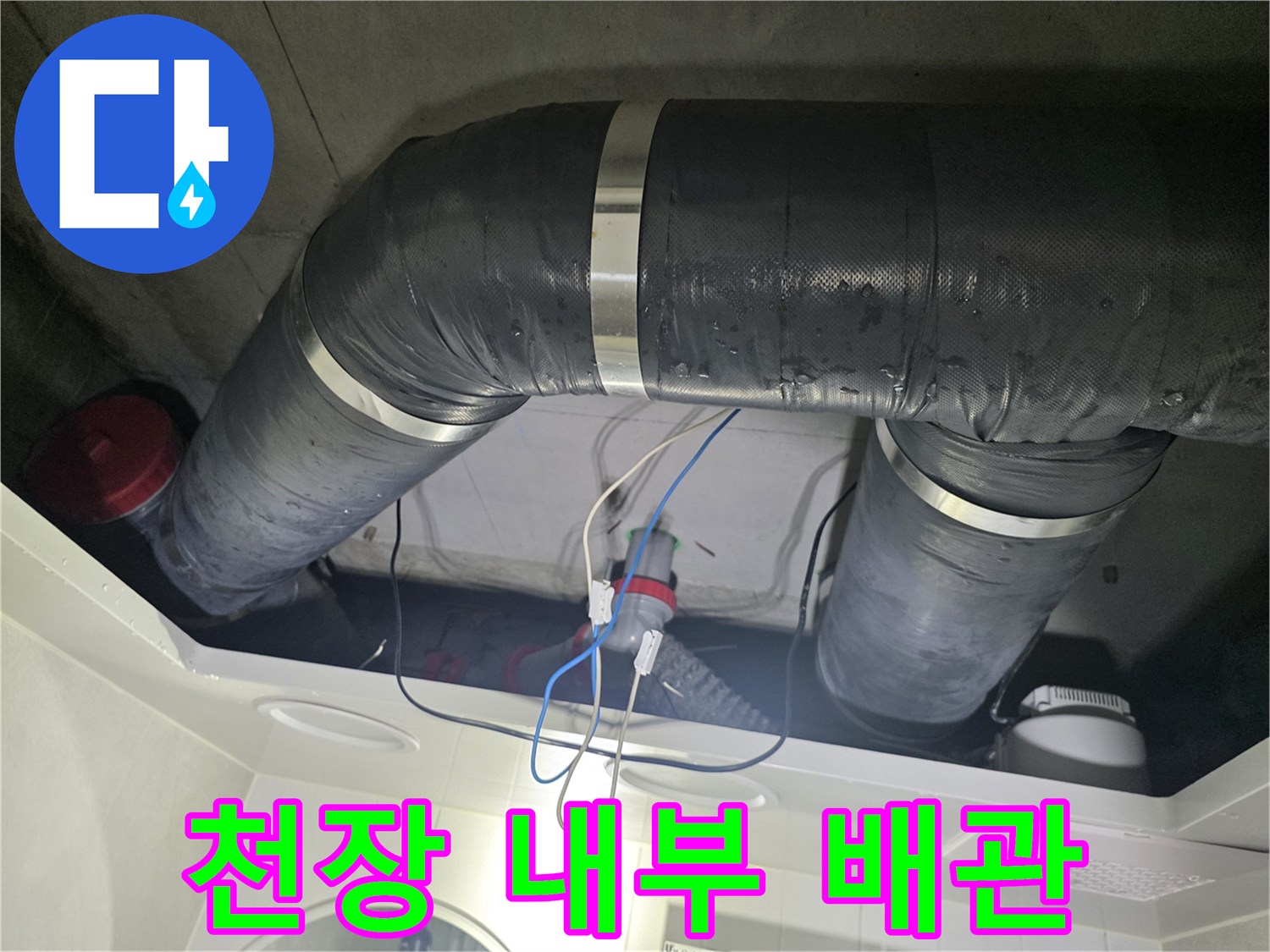 천장 구조물 사이로 보이는 검은색 배수 배관과 연결 부위