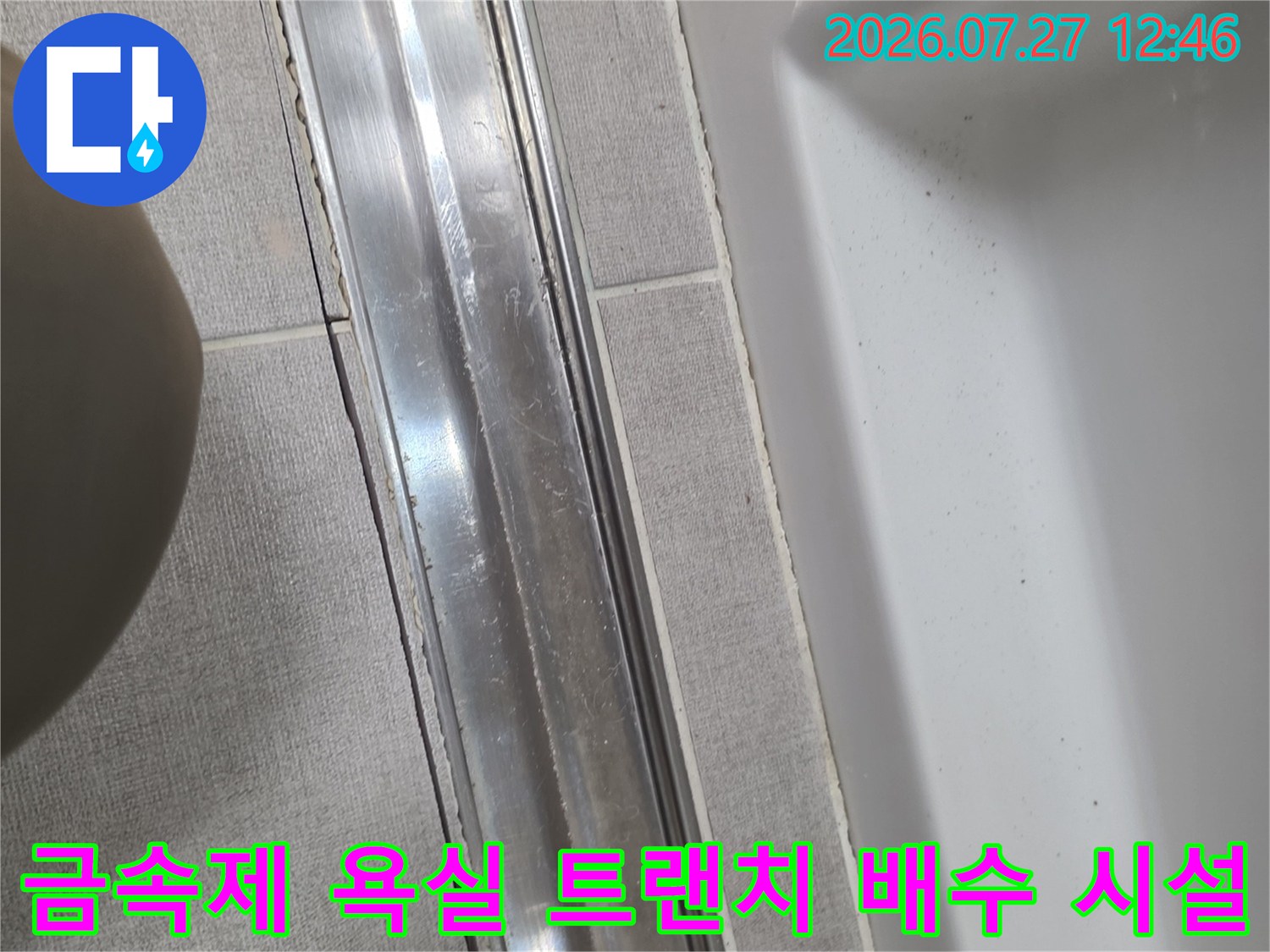 밝은 회색 타일과 맞닿아 있는 스테인리스 재질의 가로형 배수구-트랜치 상세 사진
