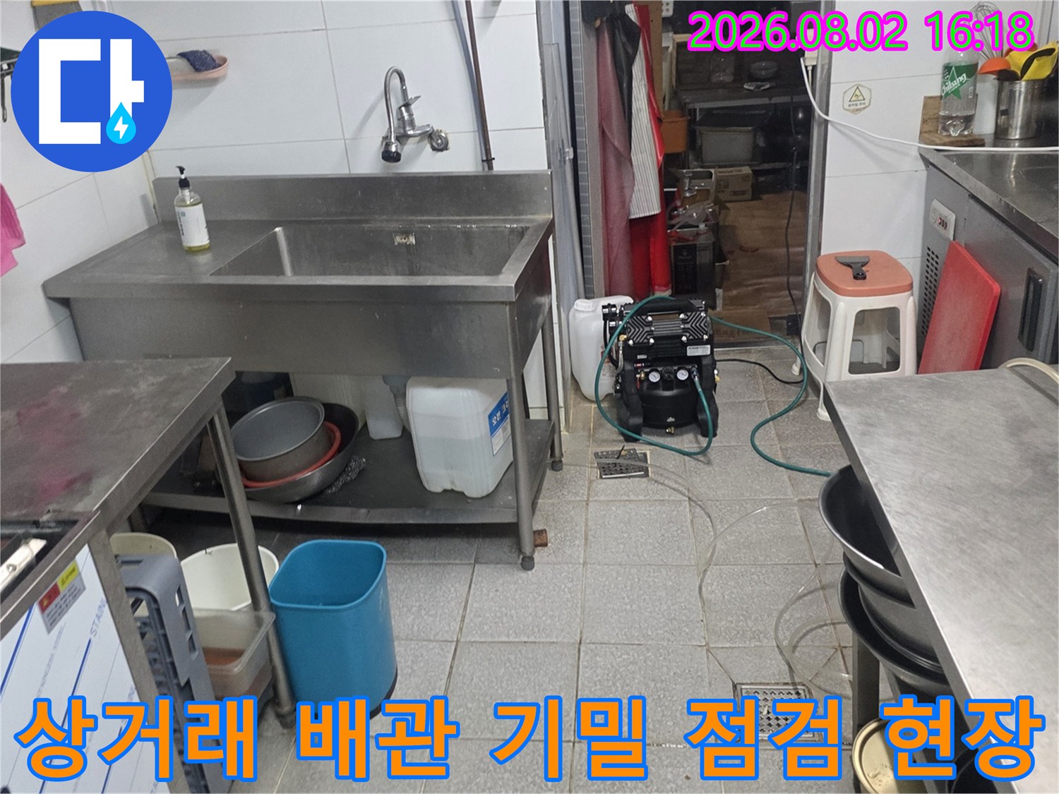 상업 공간 싱크대 하부에서 전문 장비를 연결하여 배관의 압력 및 누수 여부를 확인하는 과정입니다.