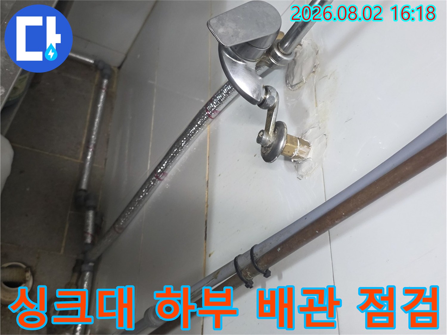 상업용 싱크대 아래 노출된 은색 배관과 연결 부위의 상세 모습
