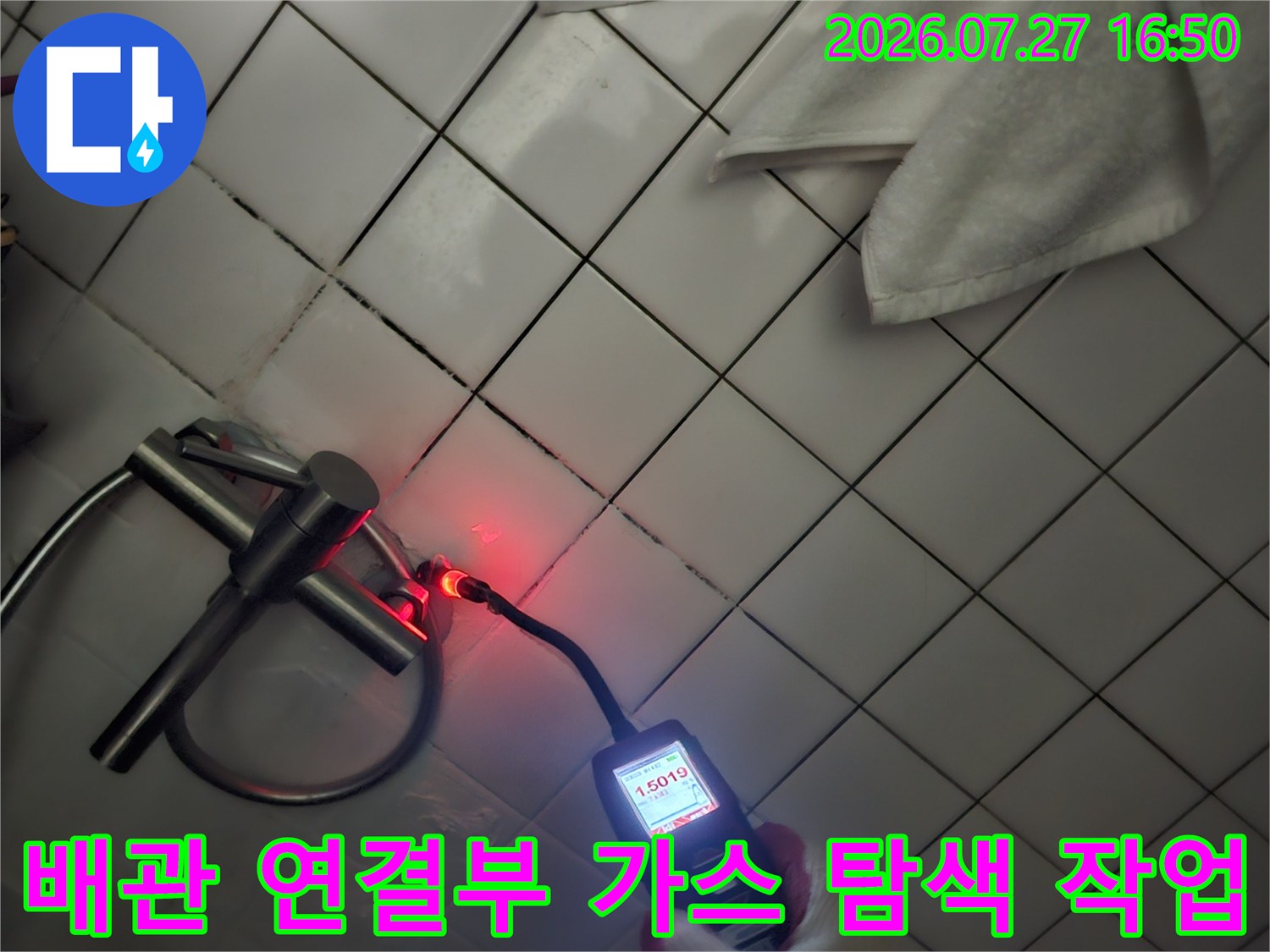 흰색 장갑을 낀 작업자가 가스 탐지기를 배관 부근에 대고 있는 모습