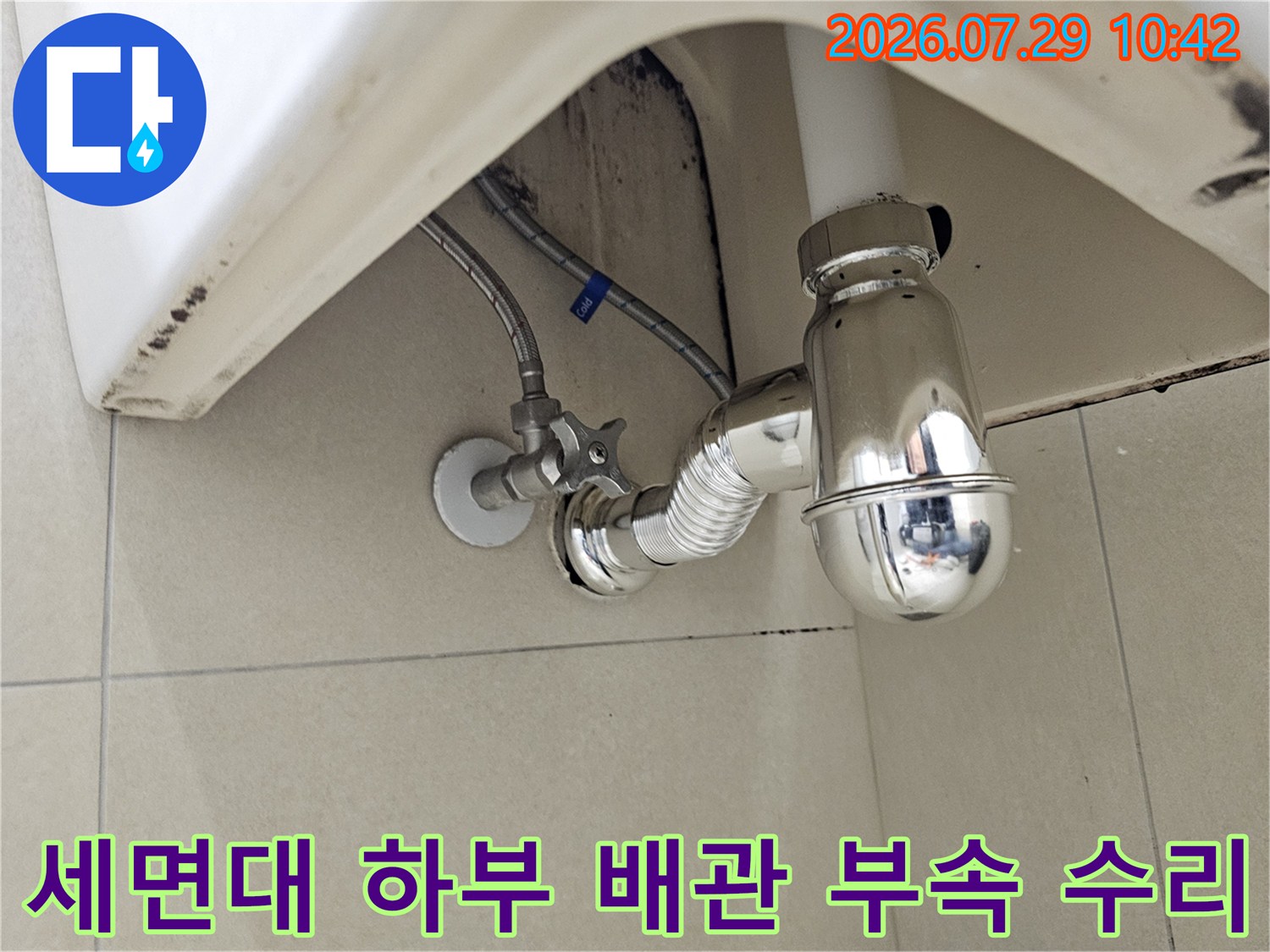 금속 트랩과 유연한 호스가 연결된 세면대 아래쪽의 복잡한 배수 경로