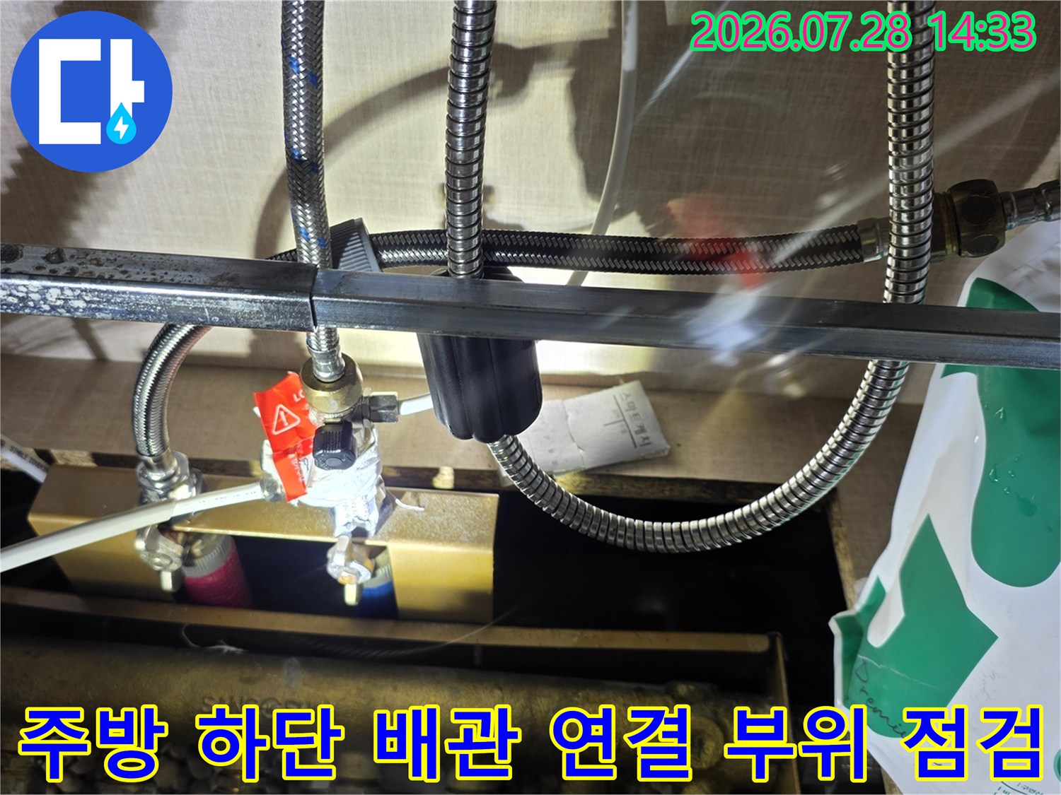 금속 재질의 분배기와 빨간색 핸들 밸브가 주름관 호스와 연결된 모습-누수 지점