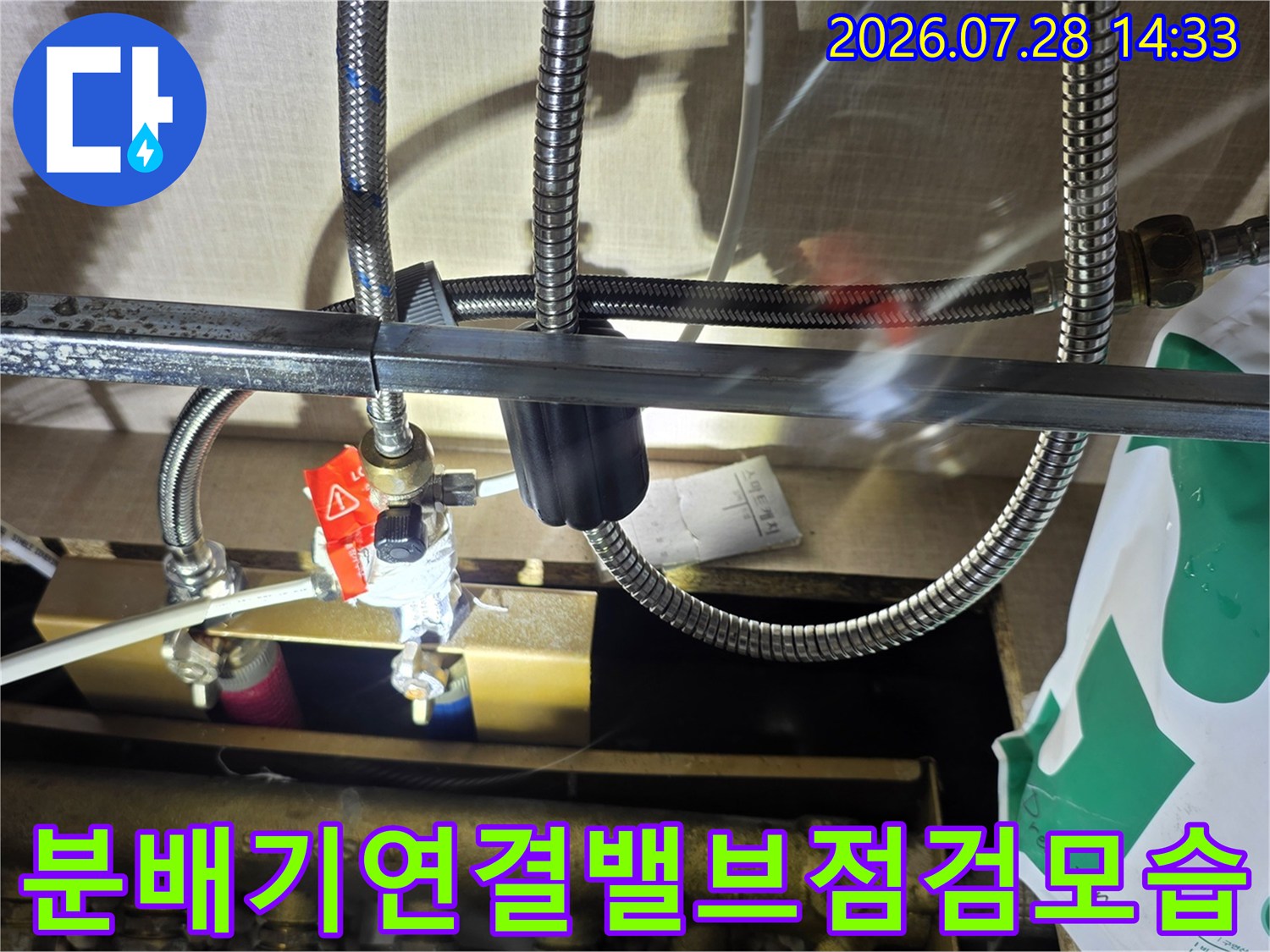 빨간색 핸들이 달린 배관 밸브와 스테인리스 주름관의 연결 상태 사진