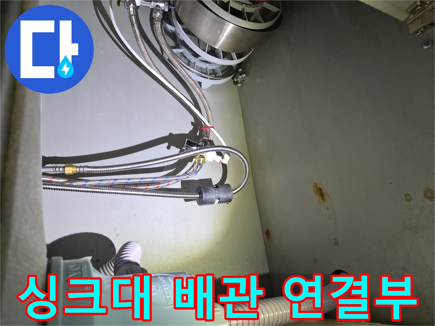 식기세척기 호스와 수전 어댑터가 연결된 싱크대 하부장 내부 상황입니다.