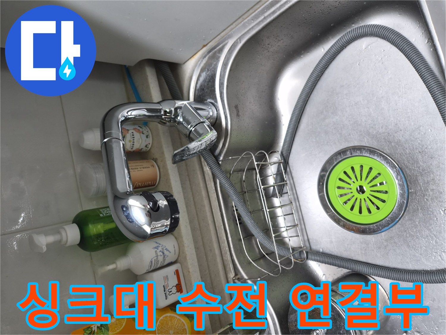 싱크대 내부의 수전 몸체와 굵은 호스가 연결된 모습입니다.