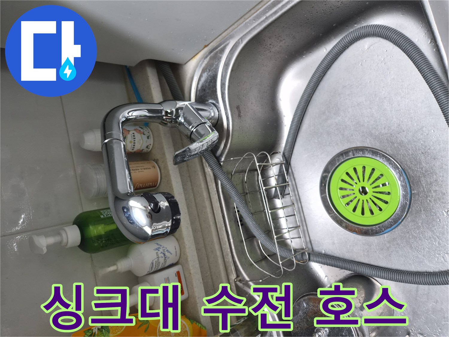 싱크대 아래쪽 수전 연결 호스와 스테인리스 배수구가 보이는 사진입니다.