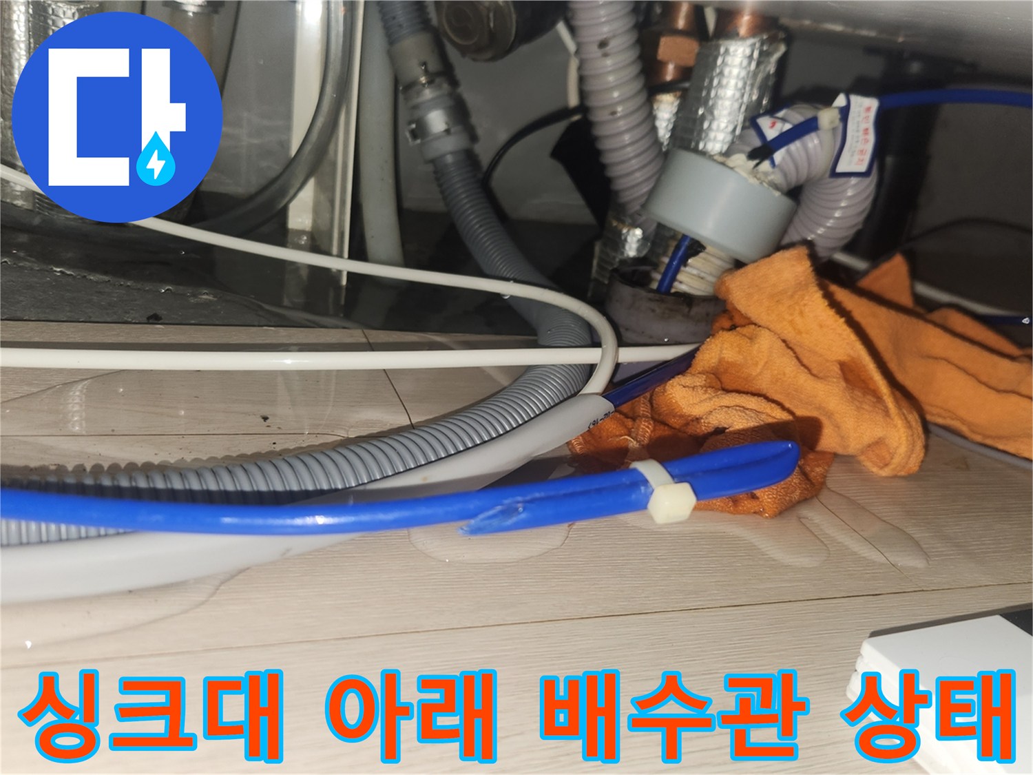 복잡하게 연결된 싱크대 배수 호스와 은색 주름관 배관