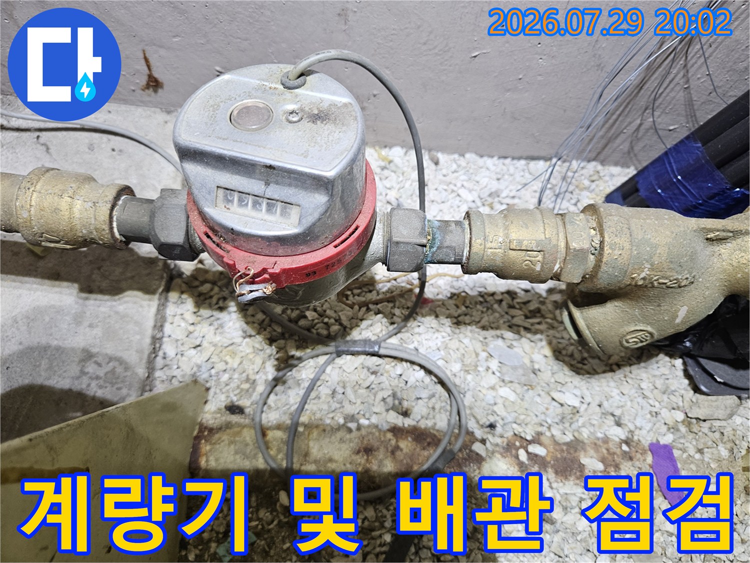 노출된 수도 계량기와 연결부의 누수 상태를 면밀히 조사하는 장면
