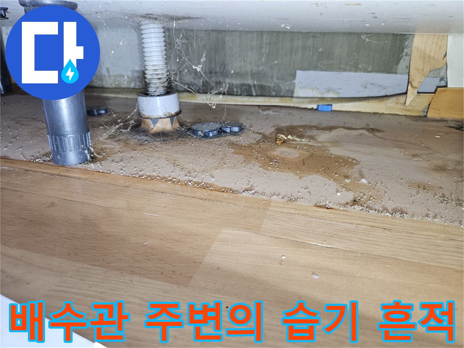 습기로 변색된 싱크대 하부 마감재와 배관 연결 부위