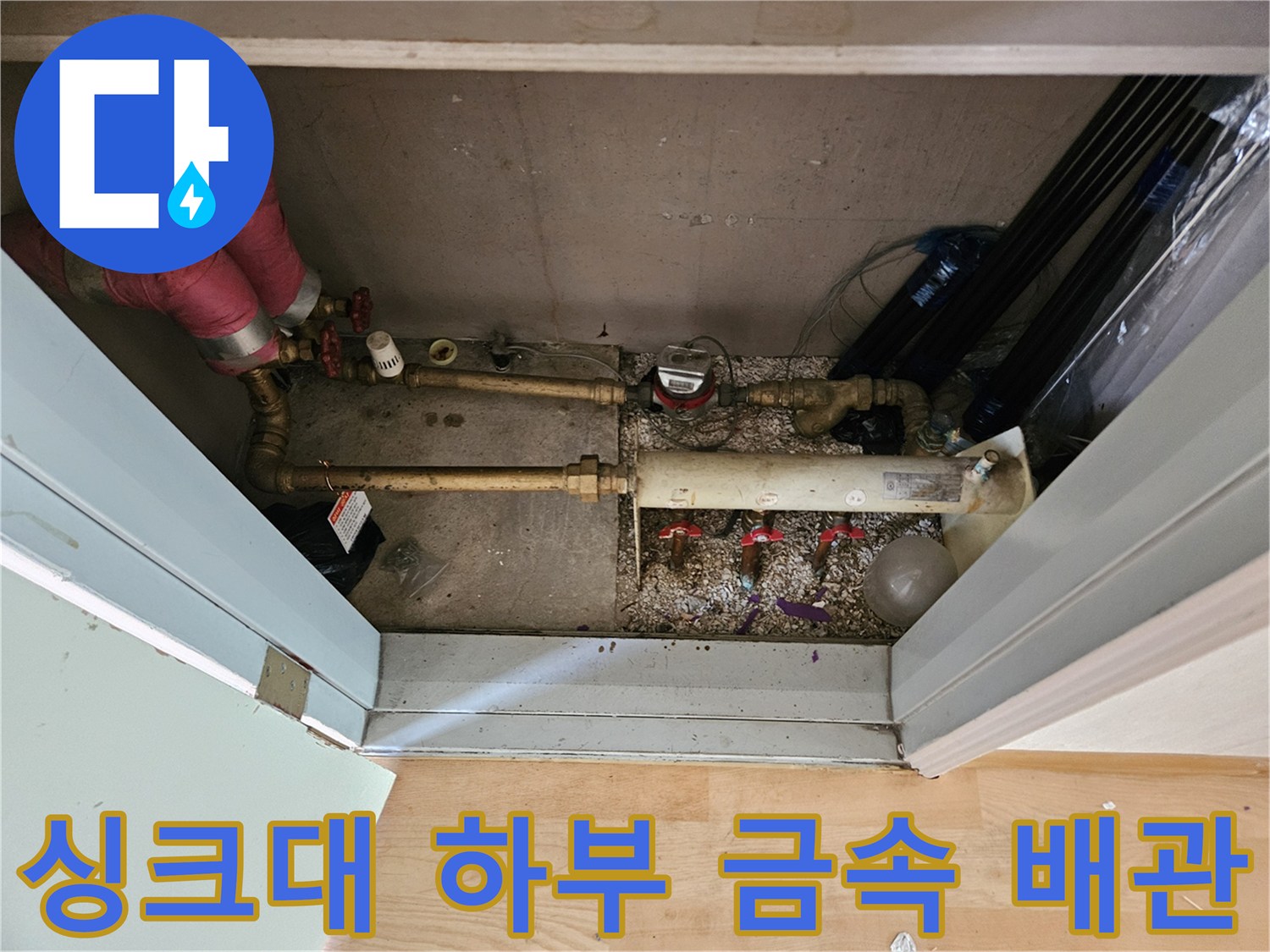 싱크대 아래쪽 은색 수도 배관과 연결된 밸브들의 모습
