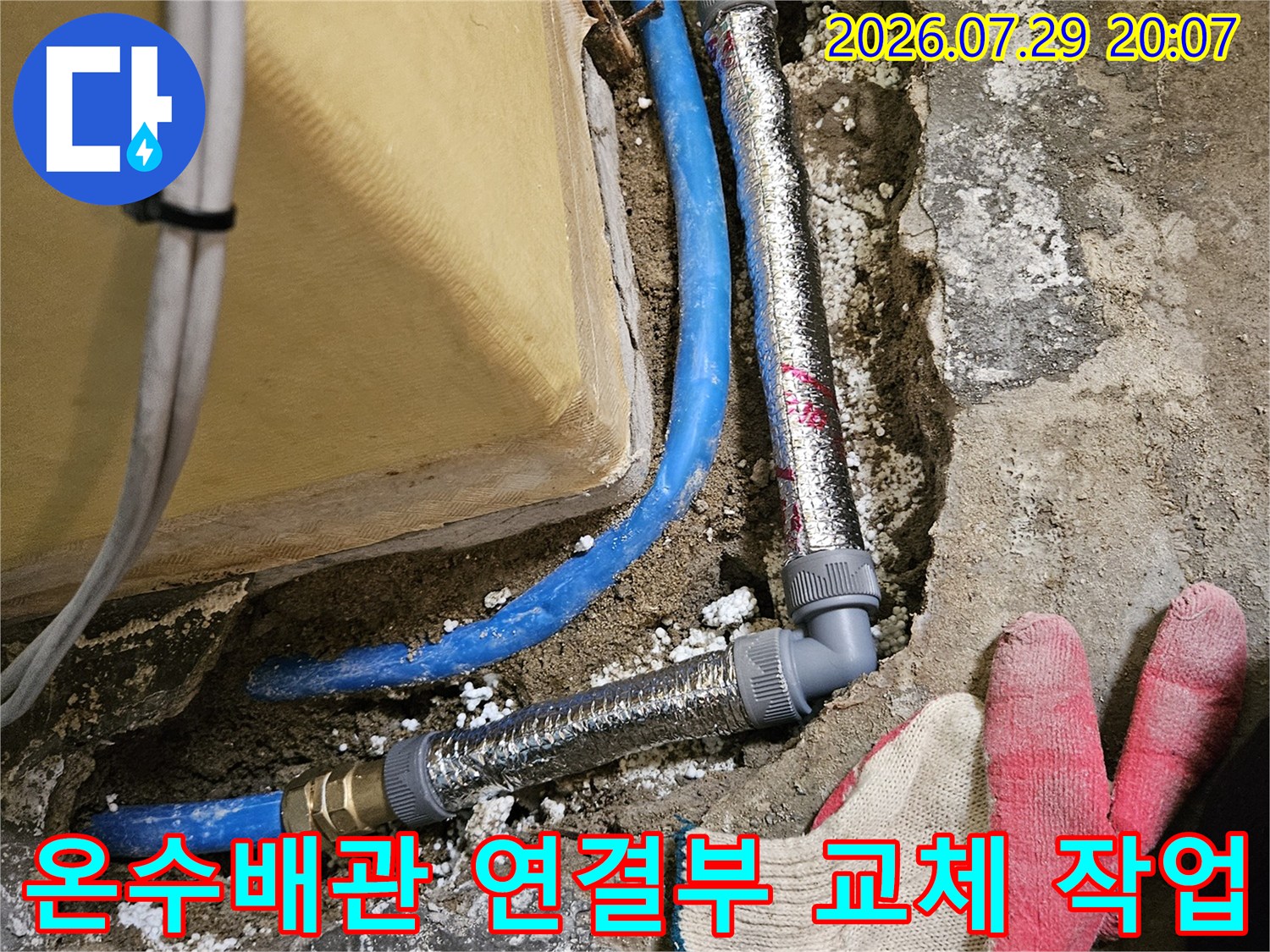 단열재가 씌워진 배관과 노출된 파란색 수도라인의 세부 수리 장면
