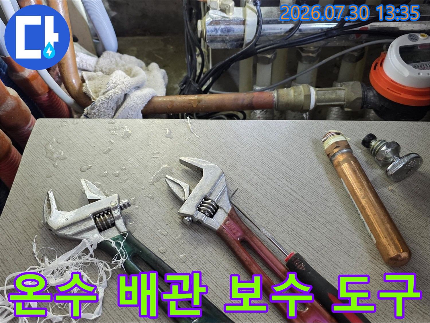 렌치와 온수 배관 자재가 놓인 배관 수리 현장 촬영