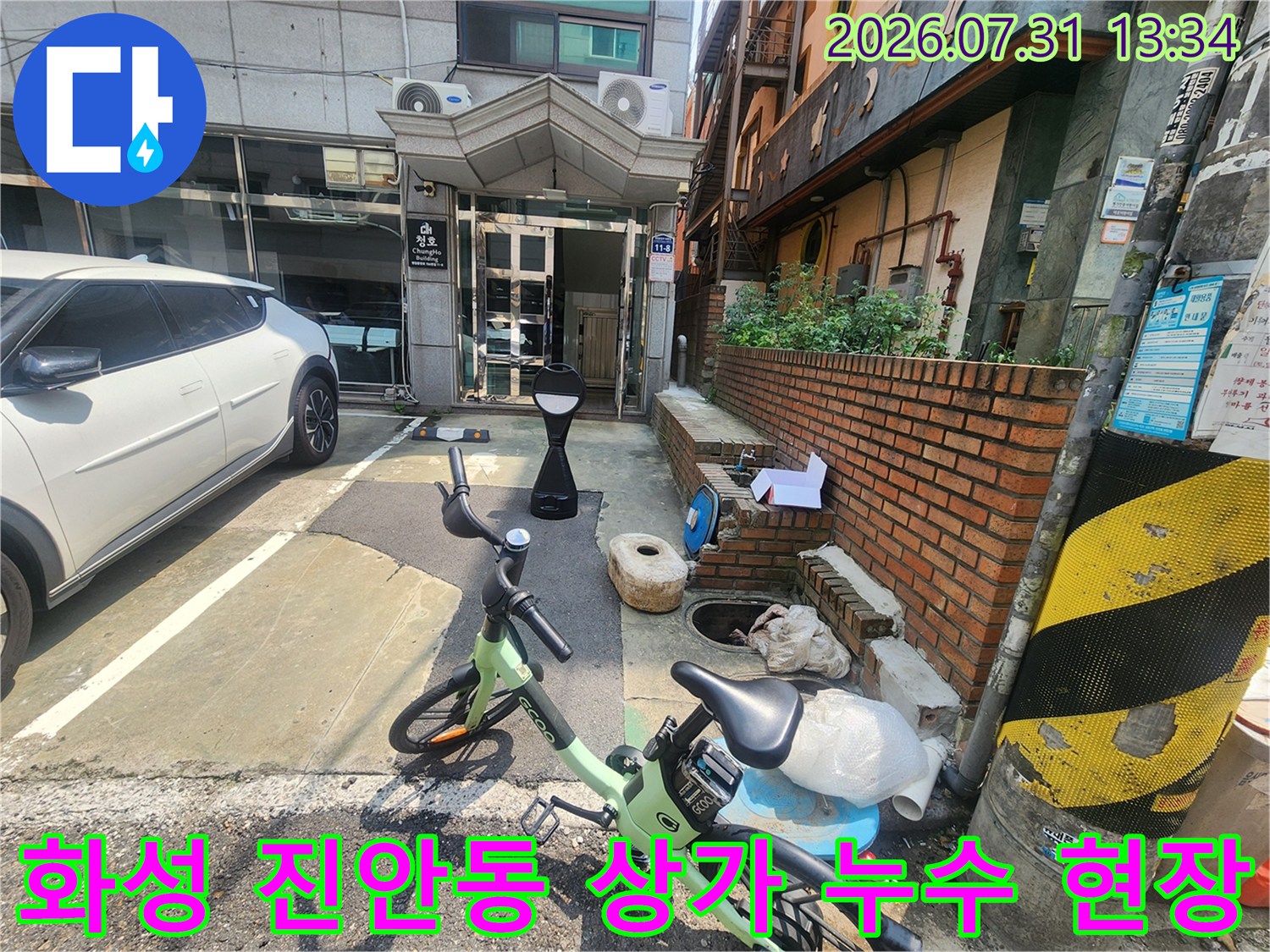 상가 건물 입구와 외부 공간에 주차된 차량 및 이동 수단이 보이는 누수 점검 현장 사진