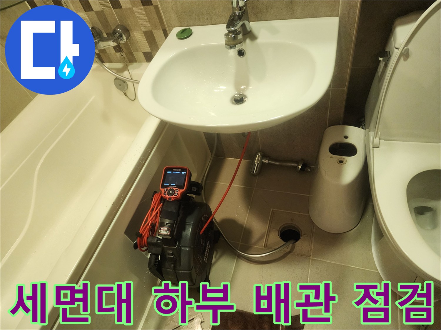 욕실 세면대 아래쪽에서 내시경 장비를 사용하여 배관 내부를 정밀하게 진단하는 모습