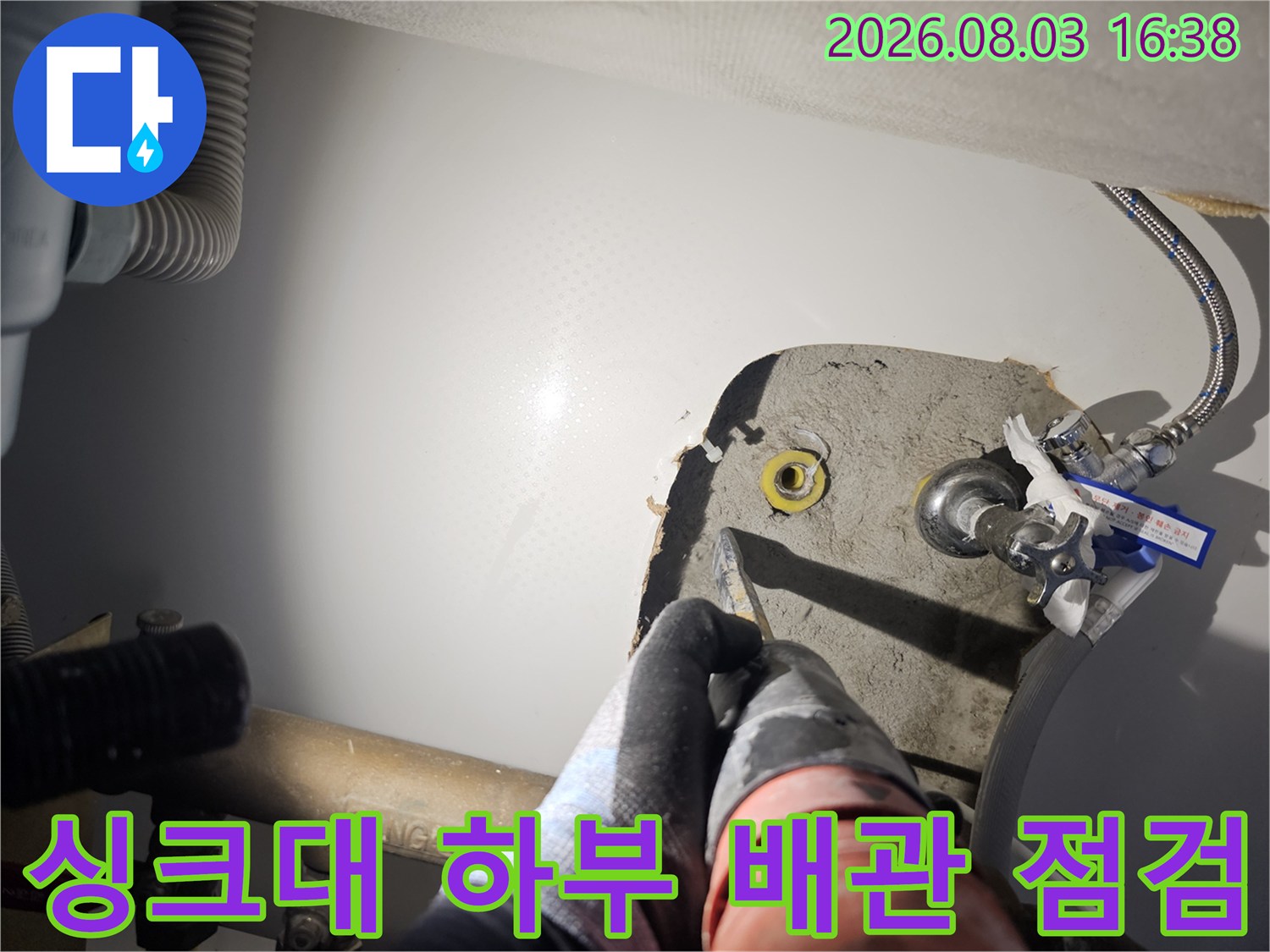 싱크대 아래 노출된 배관 연결 부위를 세밀하게 점검하는 모습