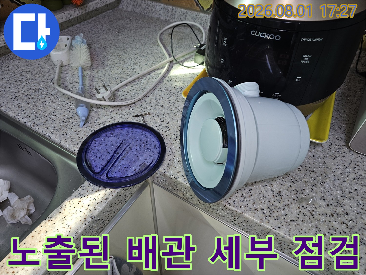 싱크대 하단부에 위치한 노출 파이프와 주변 집기들이 포함된 장면