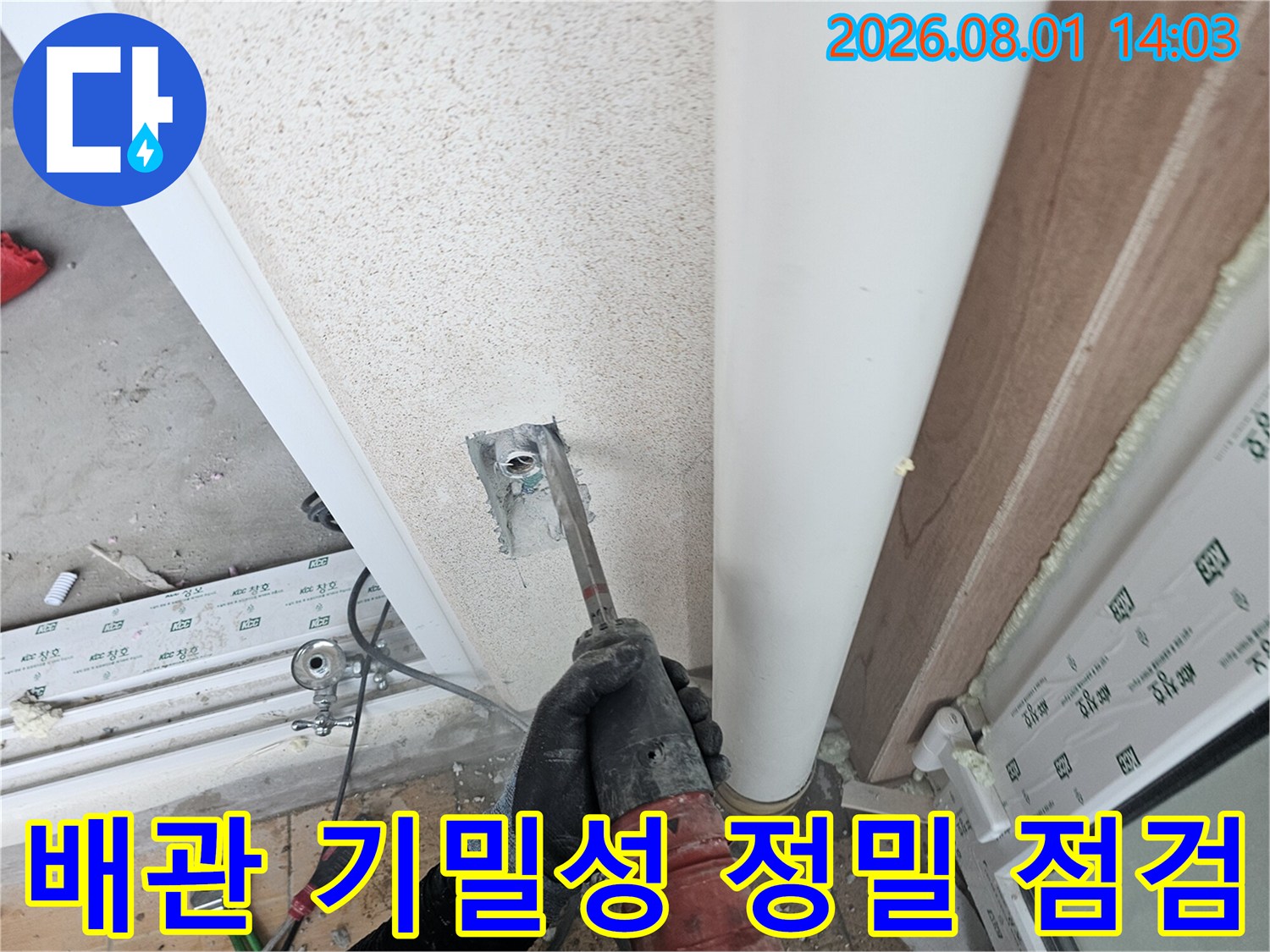 작업자가 세탁실 내부 배관 연결 부위를 장비로 꼼꼼하게 체크하는 모습