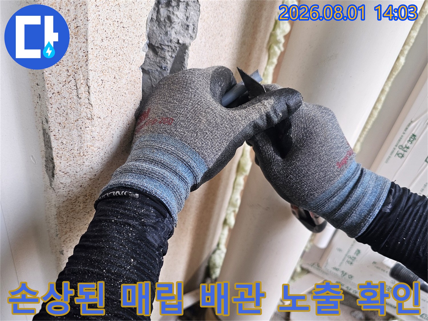 장갑을 낀 손으로 세탁실 벽면의 누수 지점을 조사하는 엔지니어의 모습