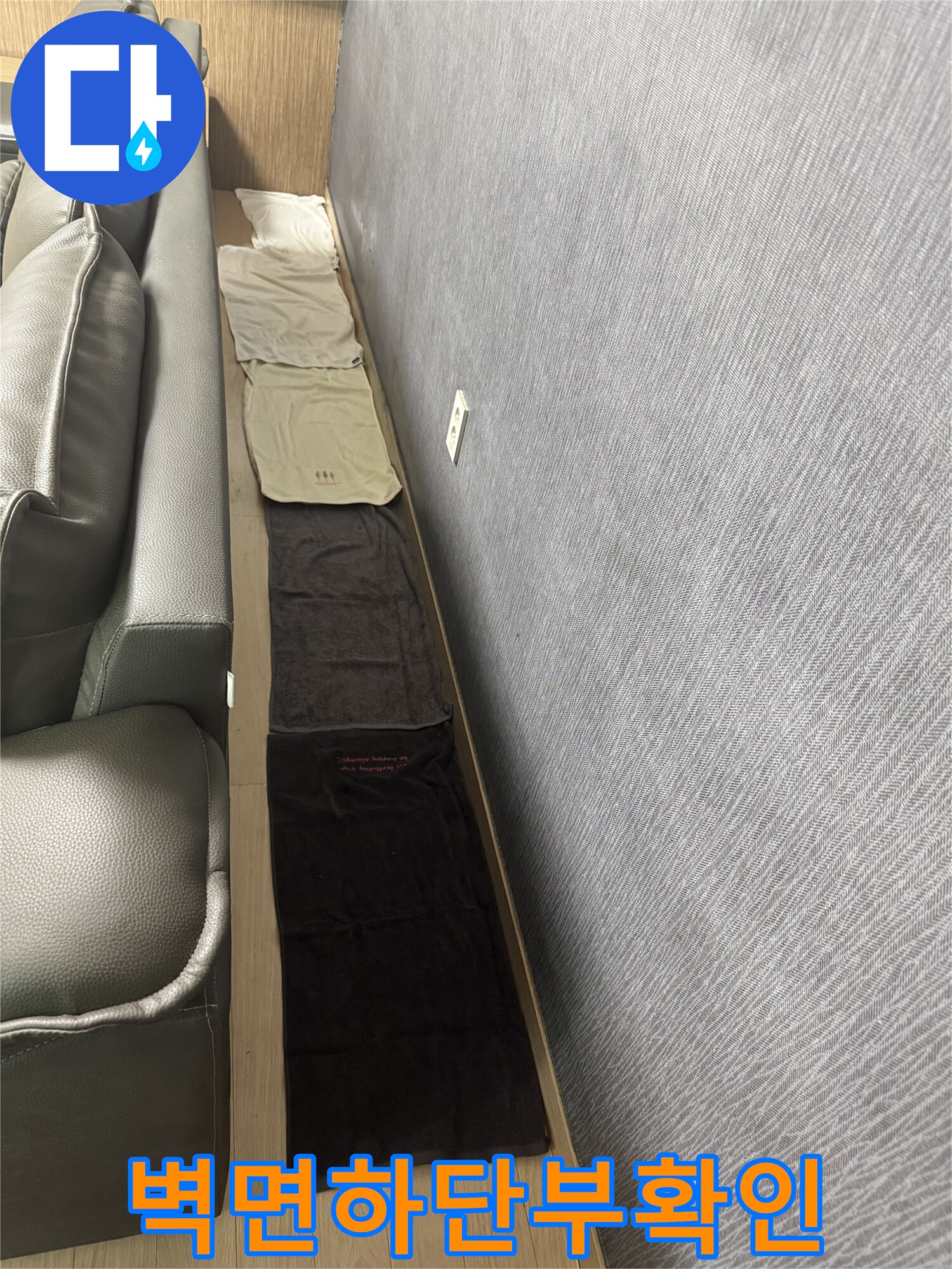 거실 소파 근처 벽지 하단부의 상태를 촬영한 사진