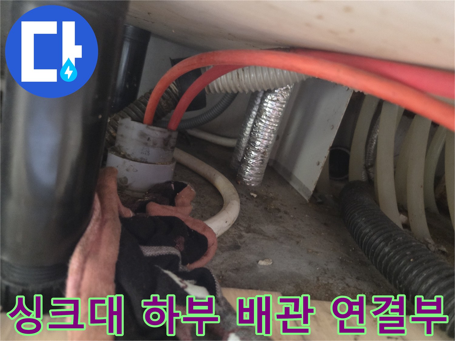 싱크대 아래쪽 굵은 배관과 주름진 호스가 보이는 내부 모습