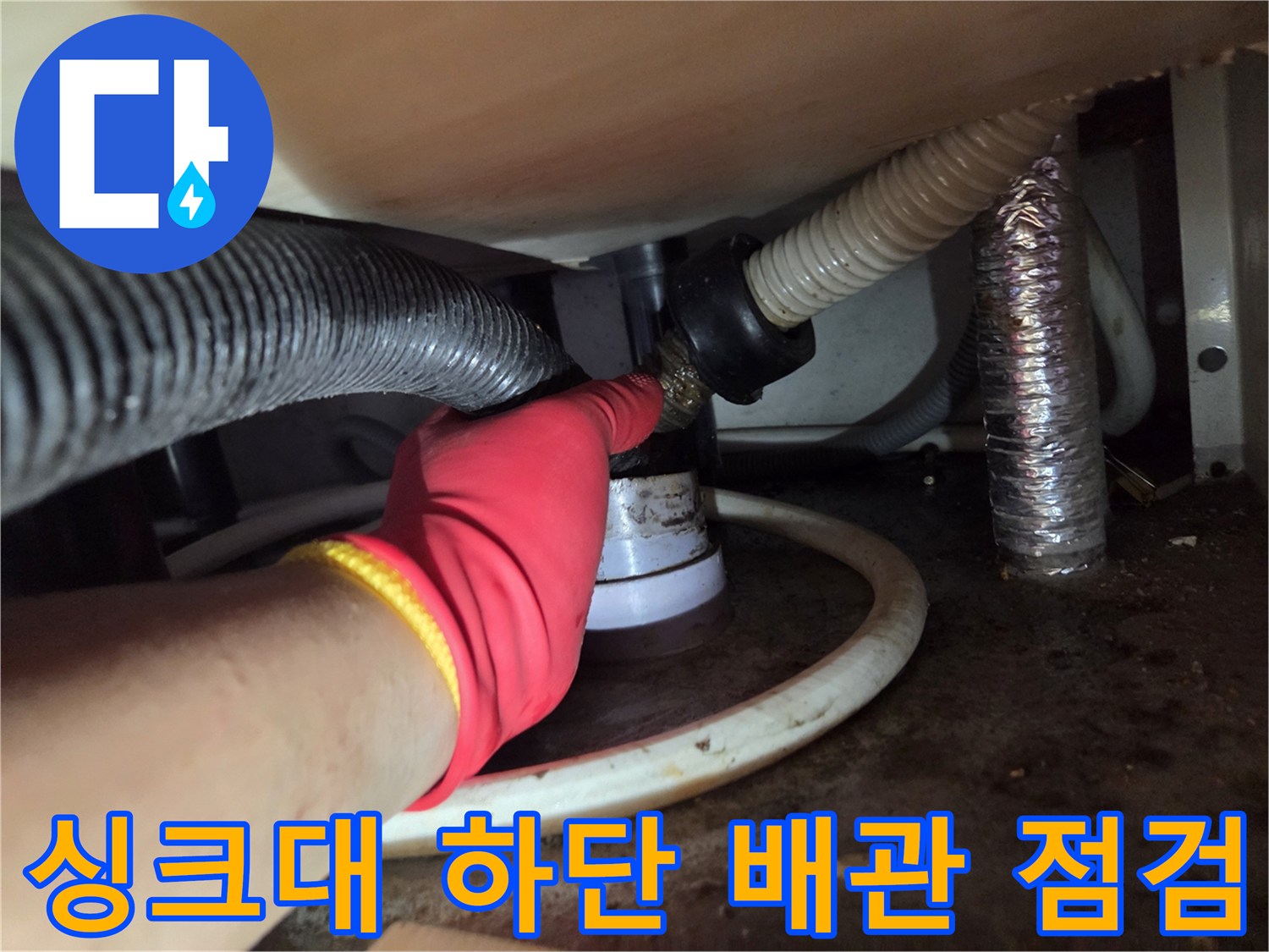 싱크대 아래쪽 굵은 주름 호스와 배수관 연결 부위를 집중적으로 보는 모습