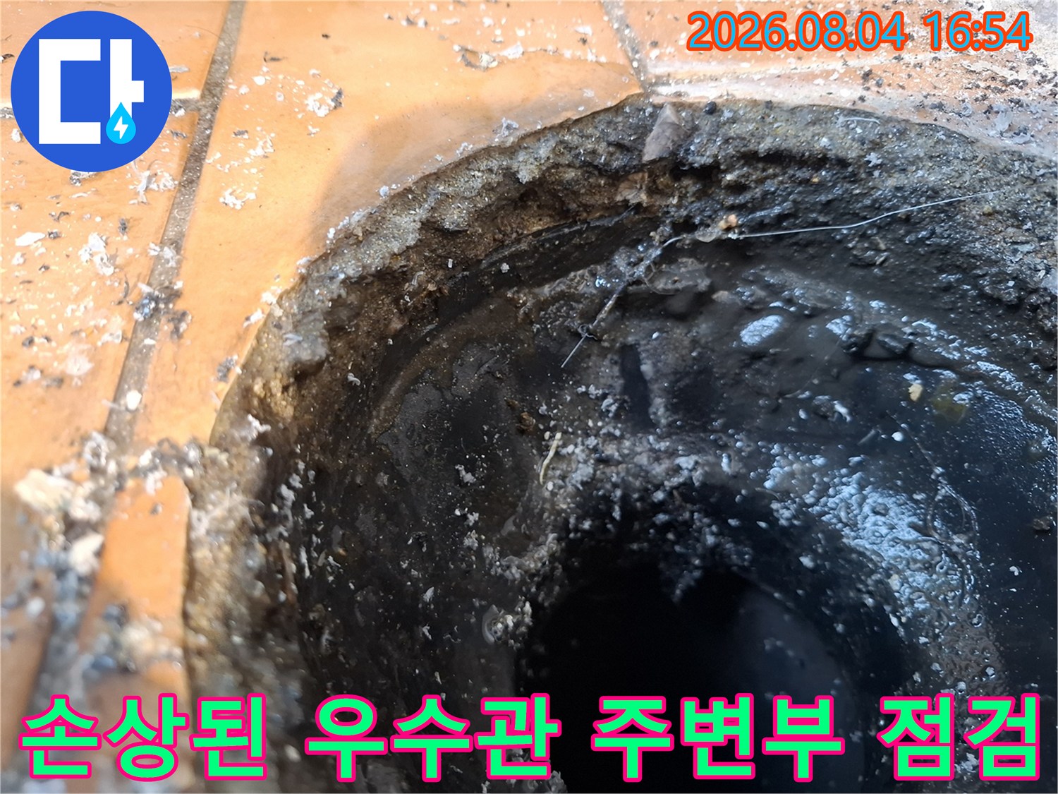 거칠게 마감된 배수구 입구와 노출된 배관 연결 부위의 클로즈업 사진