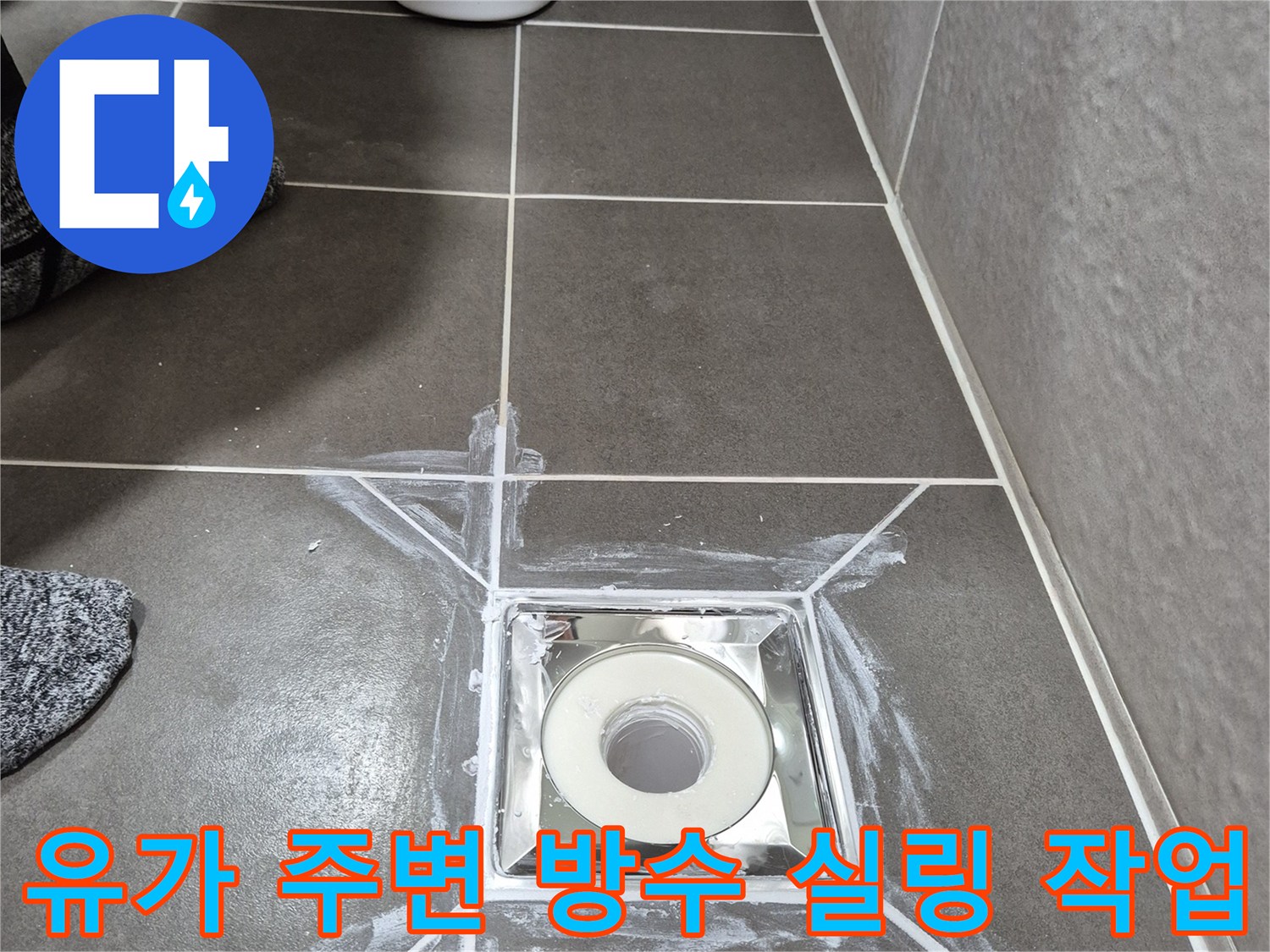 배수구 유가-타일 접합부에 하얀색 방수재를 넓게 펴 바른 현장 사진입니다.