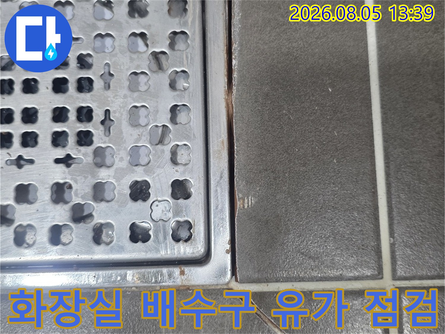 화장실 바닥에 설치된 금속 재질의 배수구 유가와 주변 타일 마감 상태