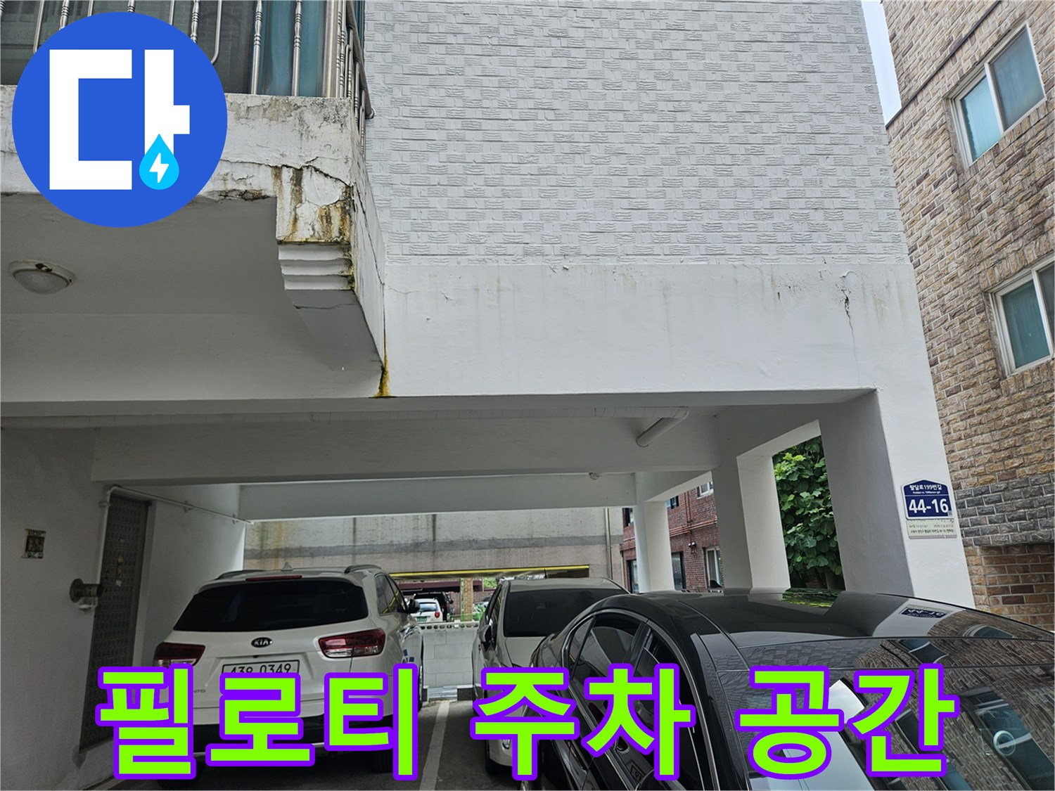 건물 하부-주차된 차량과 건물 입구 쪽 전경