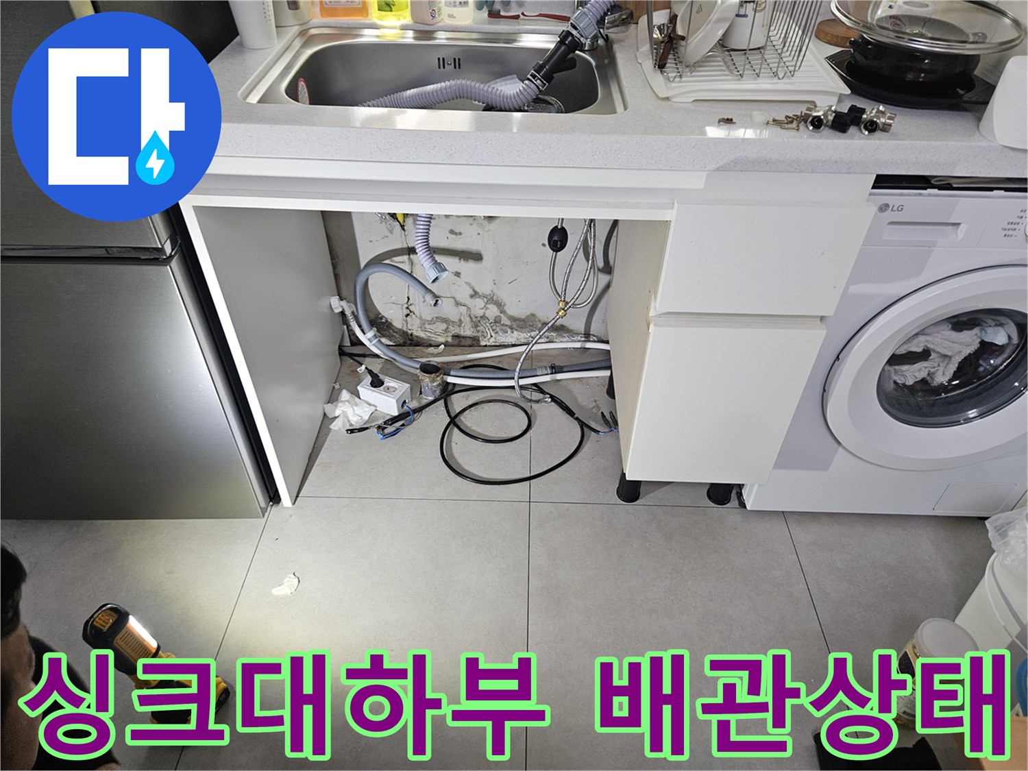 싱크대 하부장 내부의 세탁기 배관과 급수 호스 상태를 확인하는 모습