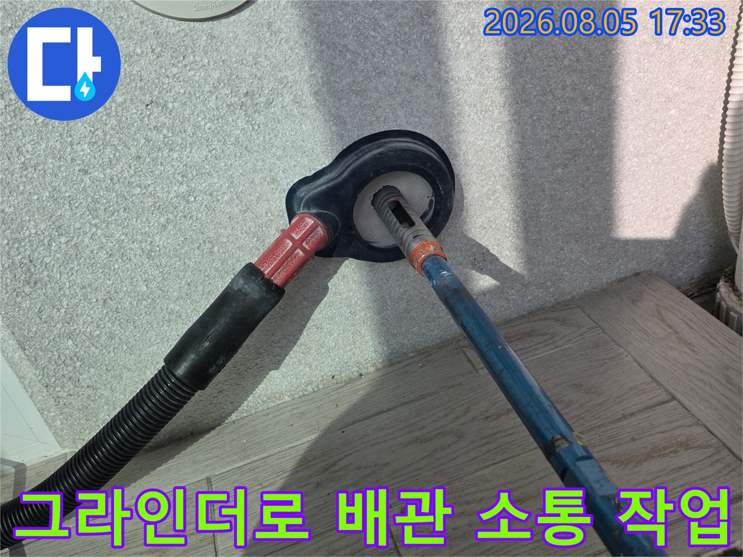 타공 장비를 사용하여 배수구 주변의 막힌 부분을 제거하는 모습