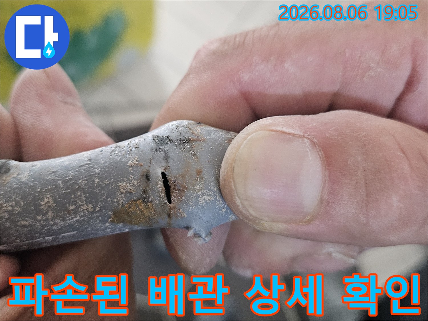손으로 잡아 들어 올린 파손 배관의 균열 부위 근접 촬영