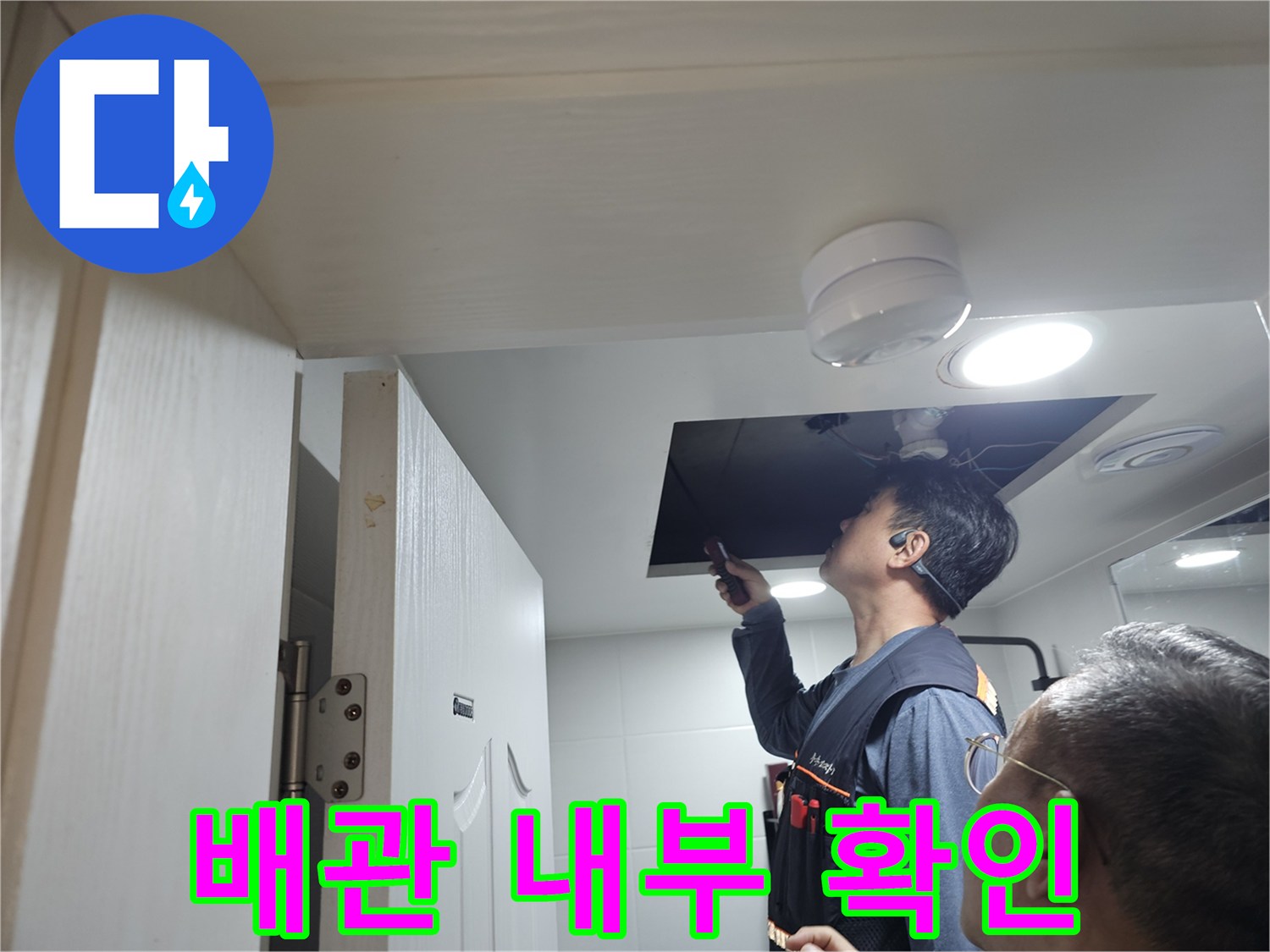 점검구-내부의-배관-연결부를-면밀히-조사하는-작업자