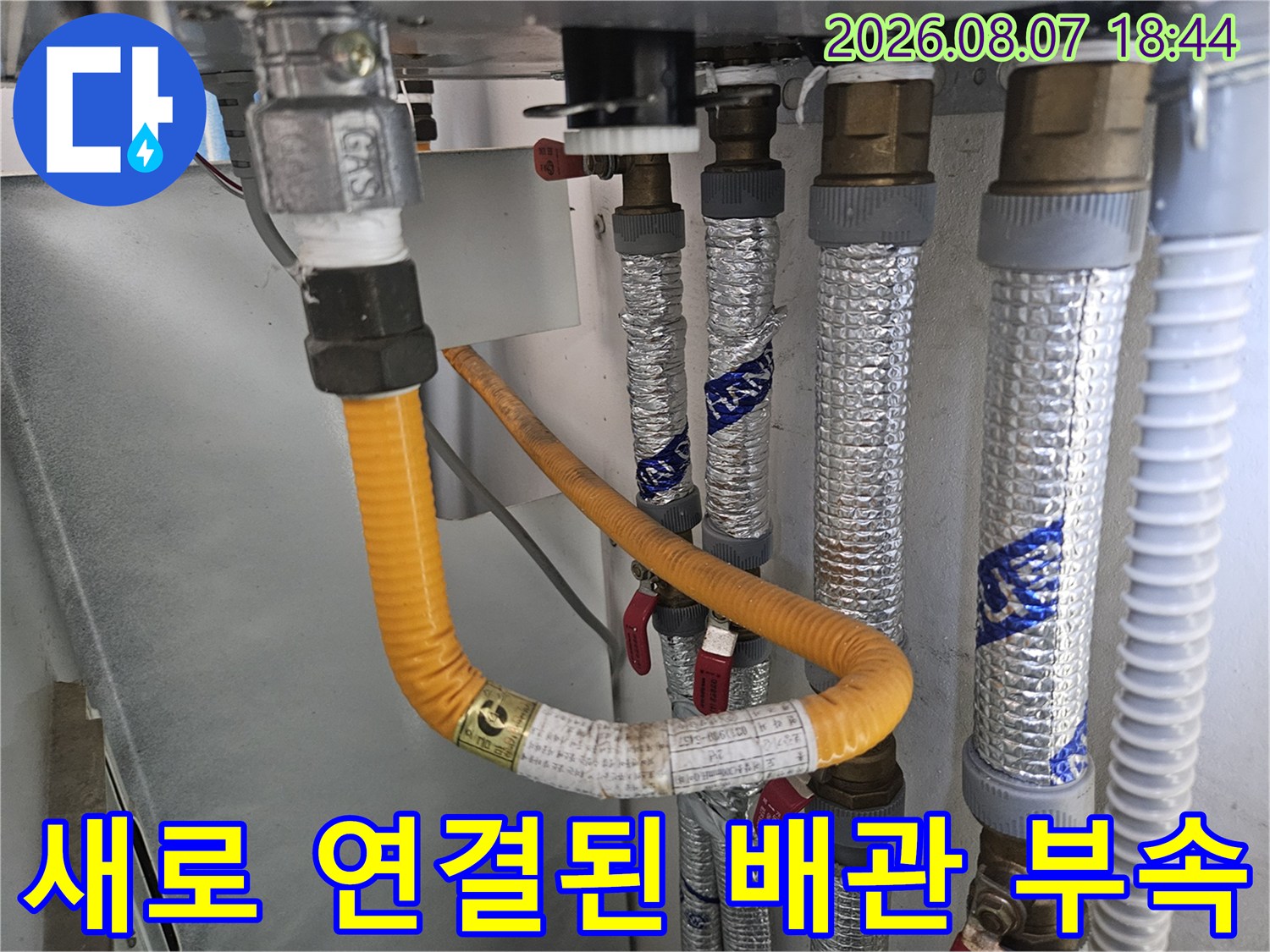 노란색 호스와 은박 보온재가 함께 설치된 수도 배관의 교체 완료 모습