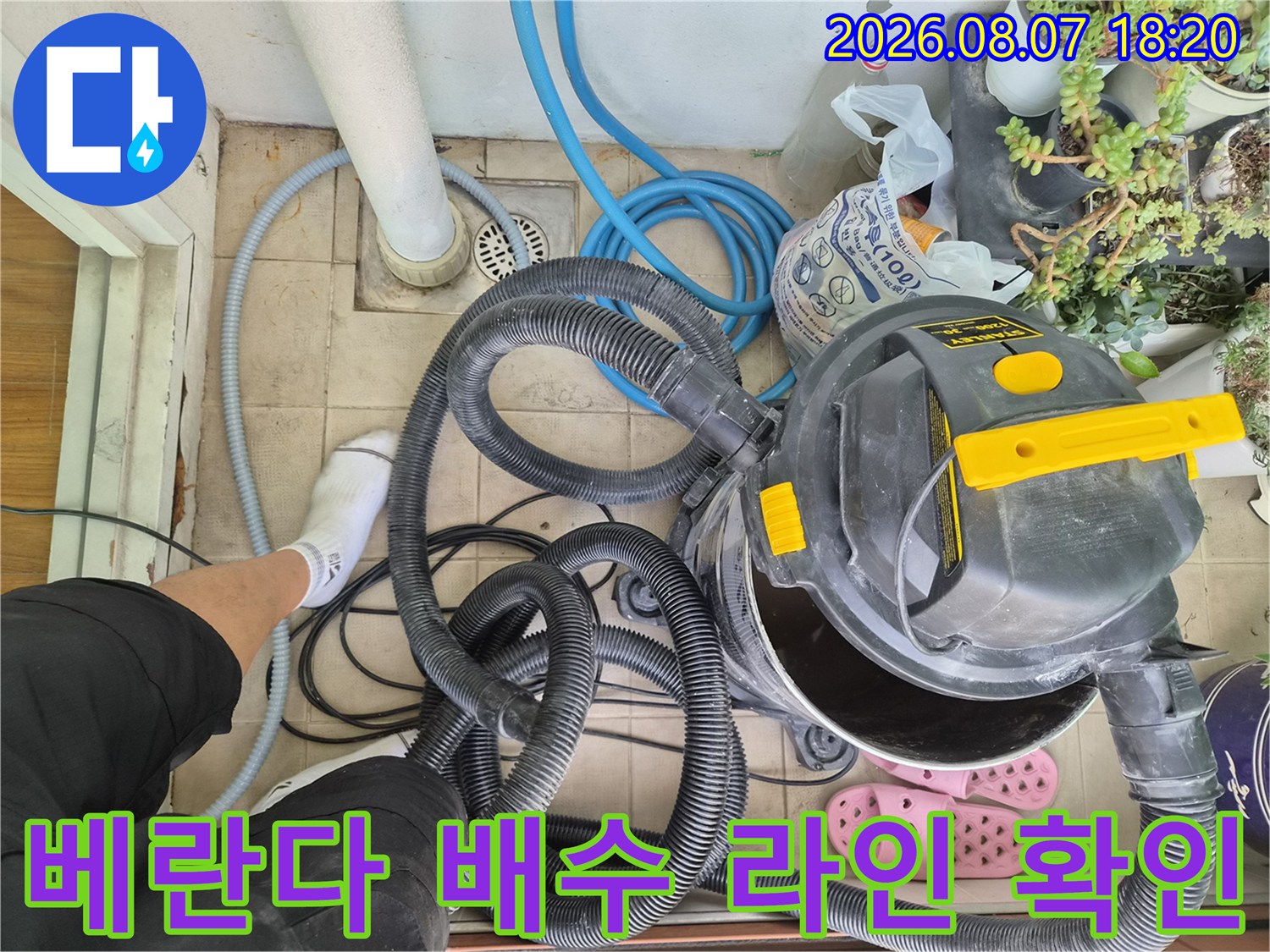 바닥 타일 위로 연결된 여러 개의 배수 호스와 청소 장비를 촬영한 사진입니다.